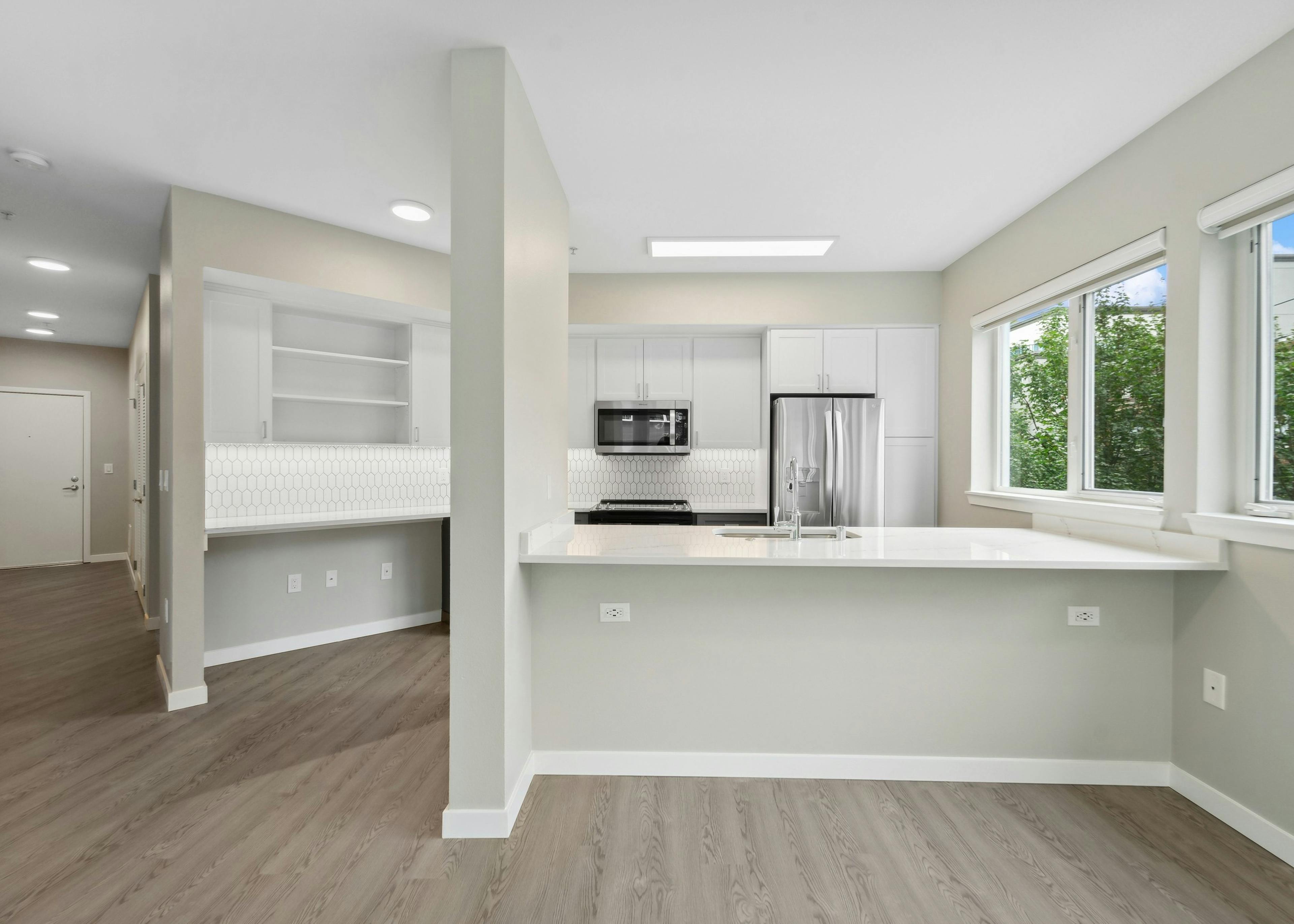 Kitchen at AMLI 535 with sink set in island and white countertops and cabinets and stainless steel appliances