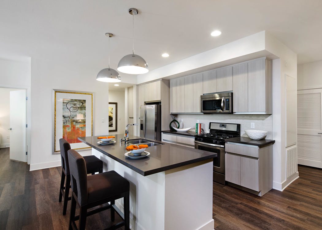 AMLI Lex on Orange apartment kitchen with light cabinetry, stone designer backsplash with quartz countertops and appliances