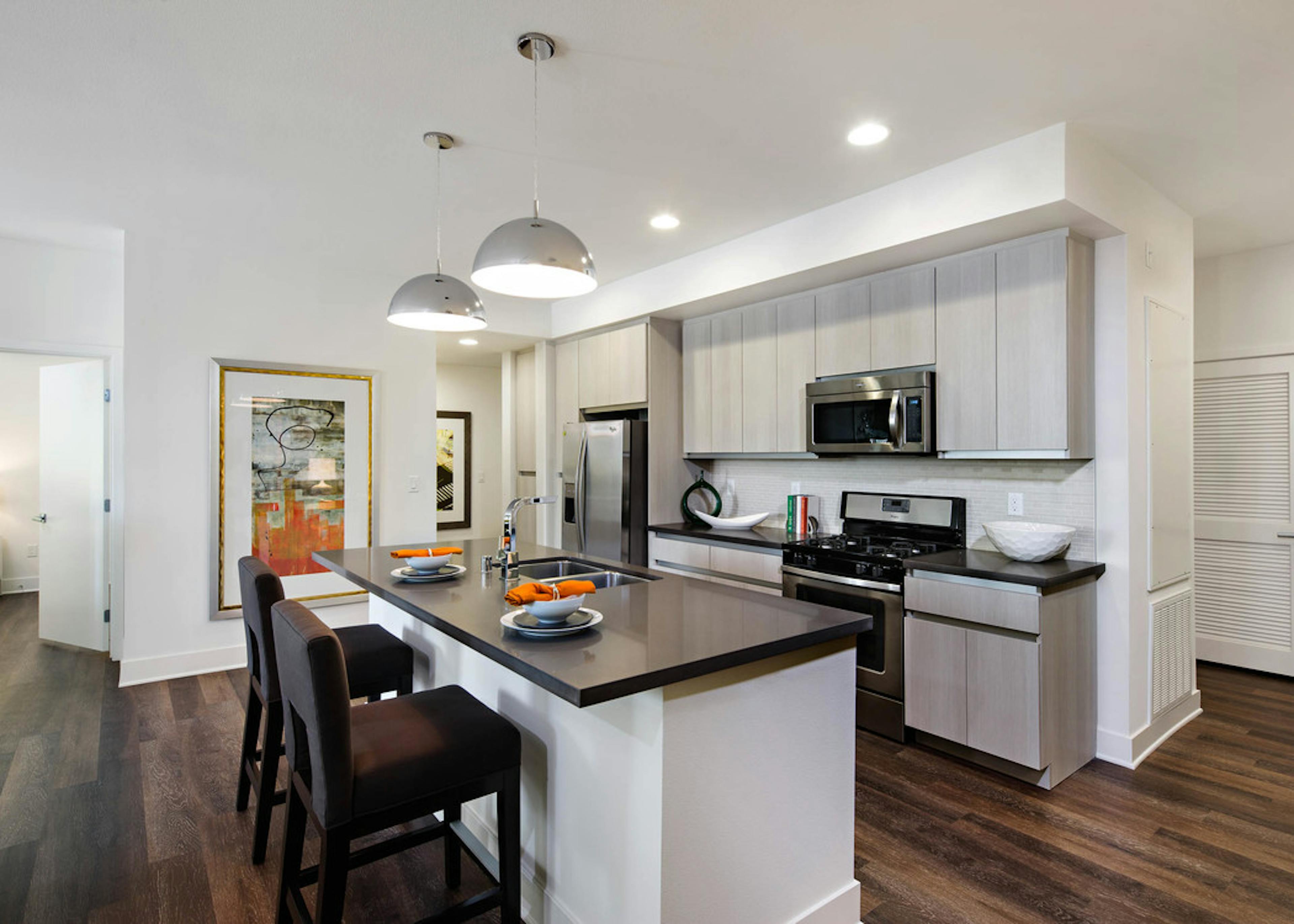 AMLI Lex on Orange apartment kitchen with light cabinetry, stone designer backsplash with quartz countertops and appliances