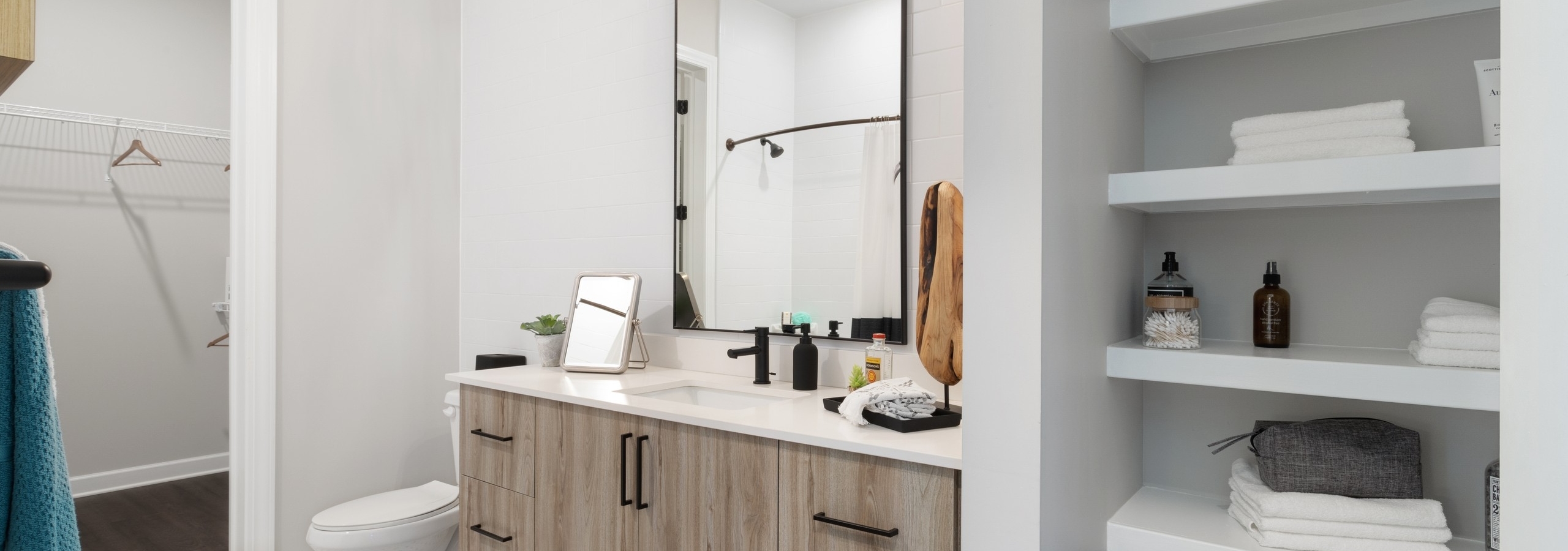 Interior bright view of bathroom with light cabinetry and tile floors and closets with shelving at AMLI Westside apartments