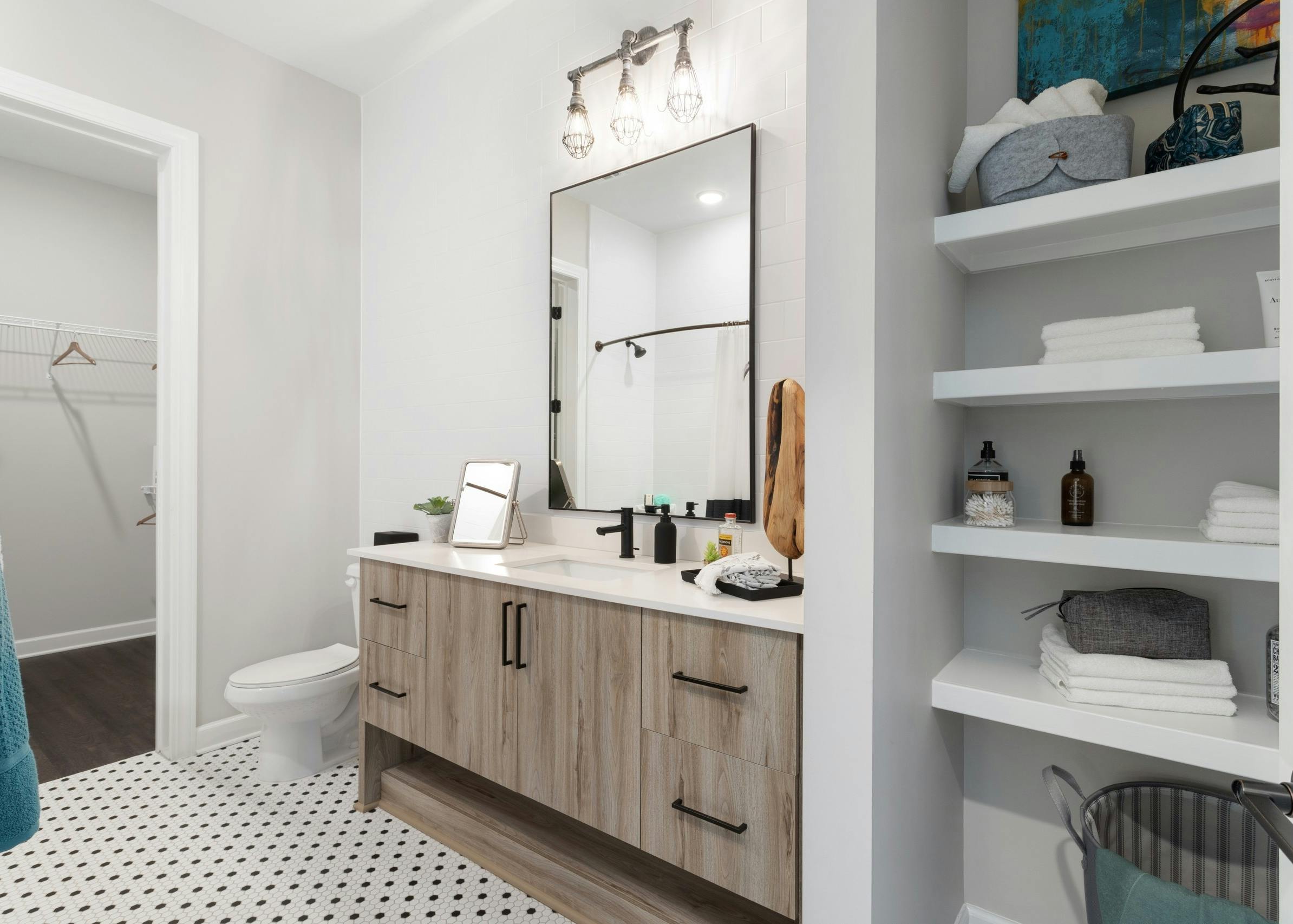 Interior bright view of bathroom with light cabinetry and tile floors and closets with shelving at AMLI Westside apartments