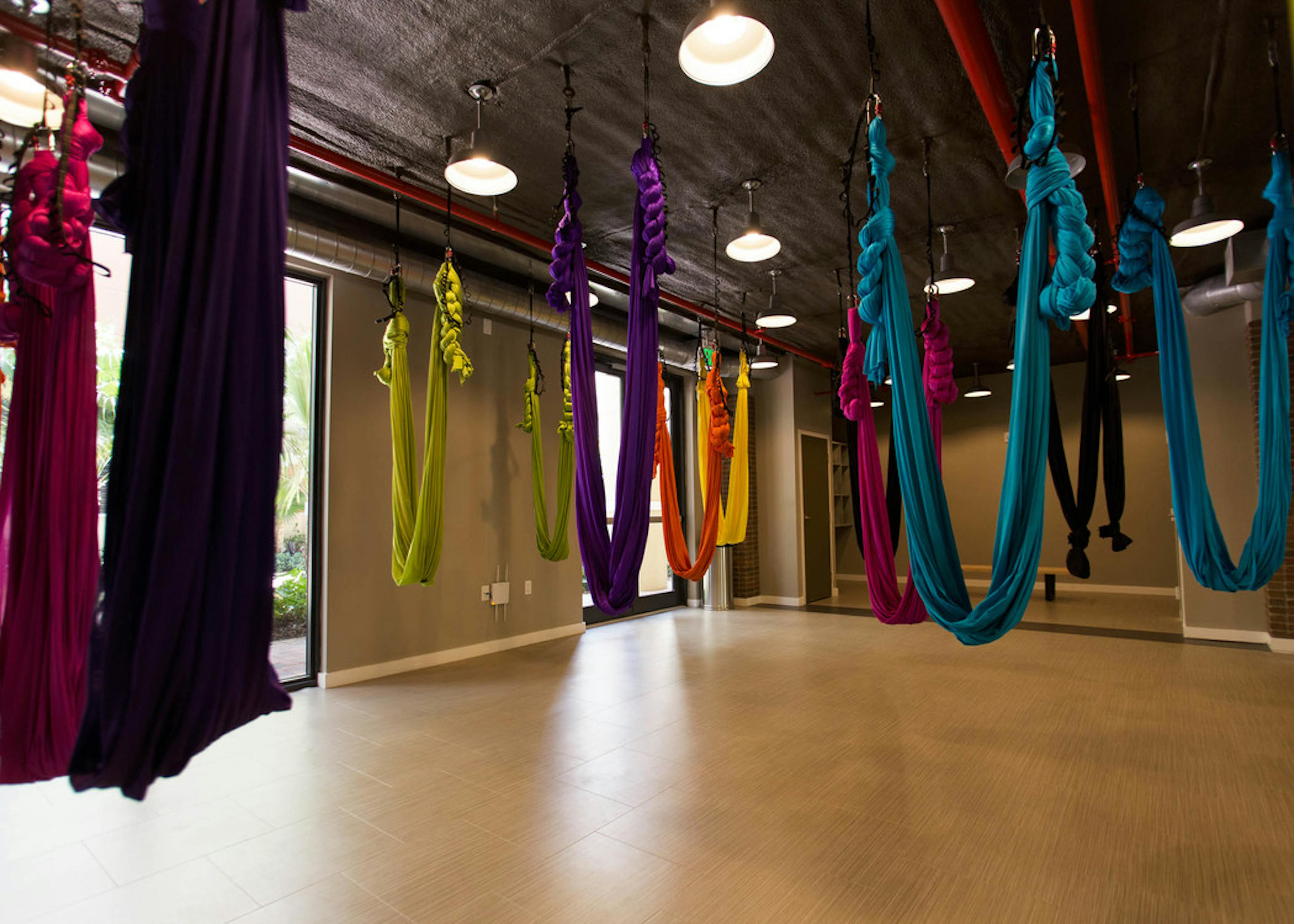 The aerial yoga studio at AMLI Dadeland with multiple vibrant colored hammocks hanging from the ceiling