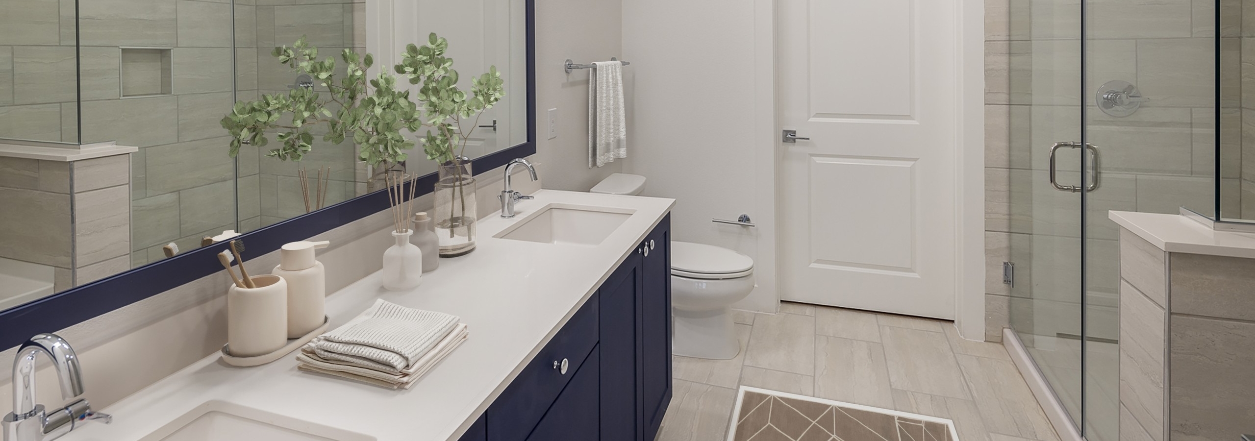 AMLI Branch Park apartment bathroom featuring long dark blue double vanity sink and white tiled floor with glass shower door
