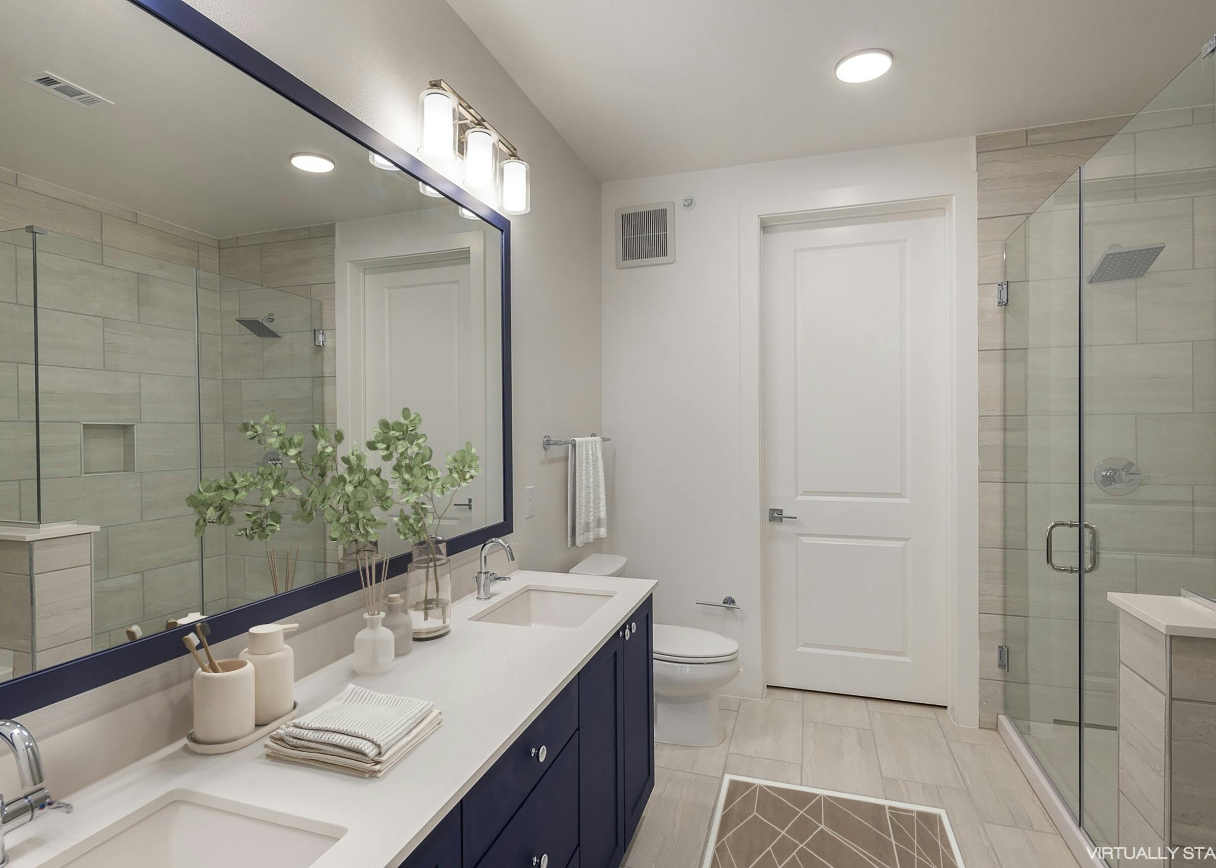 AMLI Branch Park apartment bathroom featuring long dark blue double vanity sink and white tiled floor with glass shower door