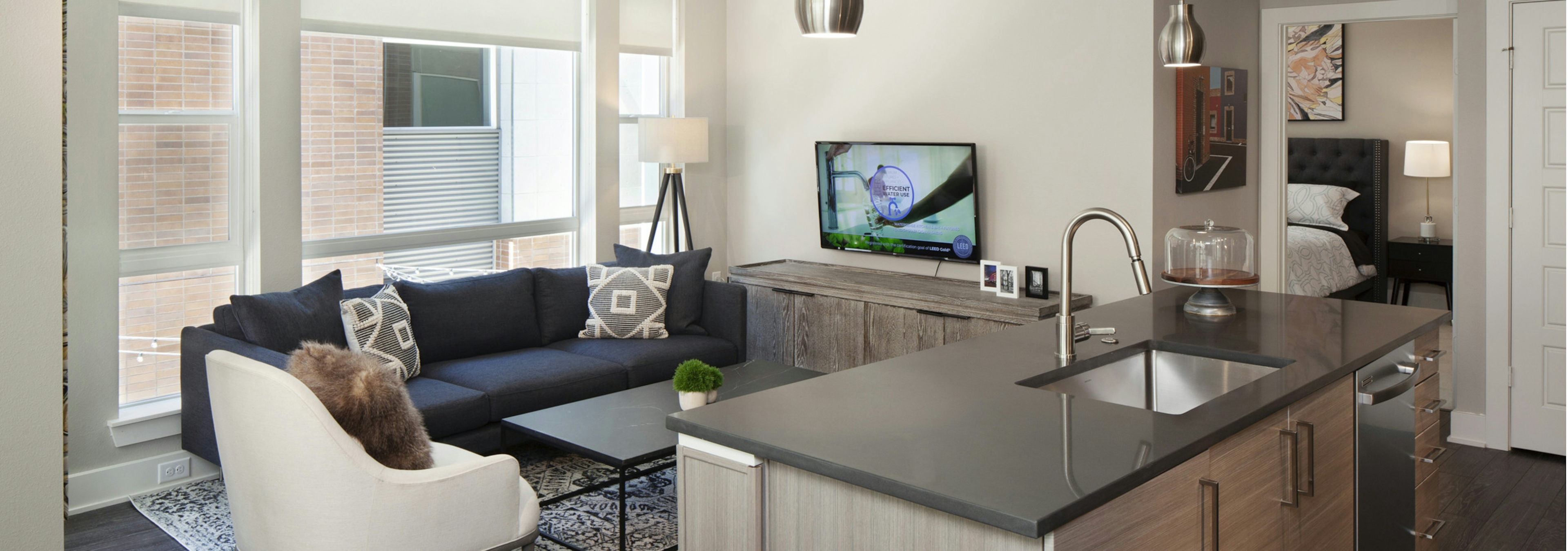 A kitchen island at AMLI Riverfront Green apartment and living room with a large window and a view into the bedroom