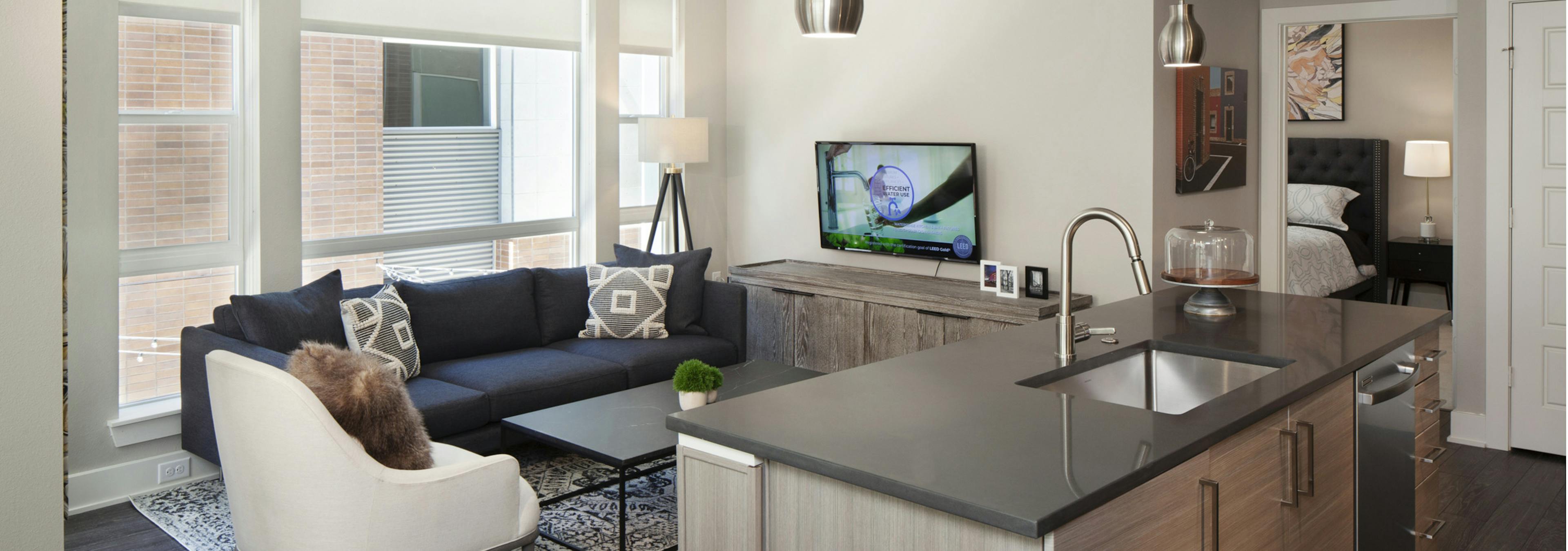 A kitchen island at AMLI Riverfront Green apartment and living room with a large window and a view into the bedroom