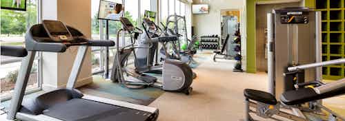 Close up view of treadmill and cardio machines in the AMLI at Mueller fitness center with beige flooring and large windows