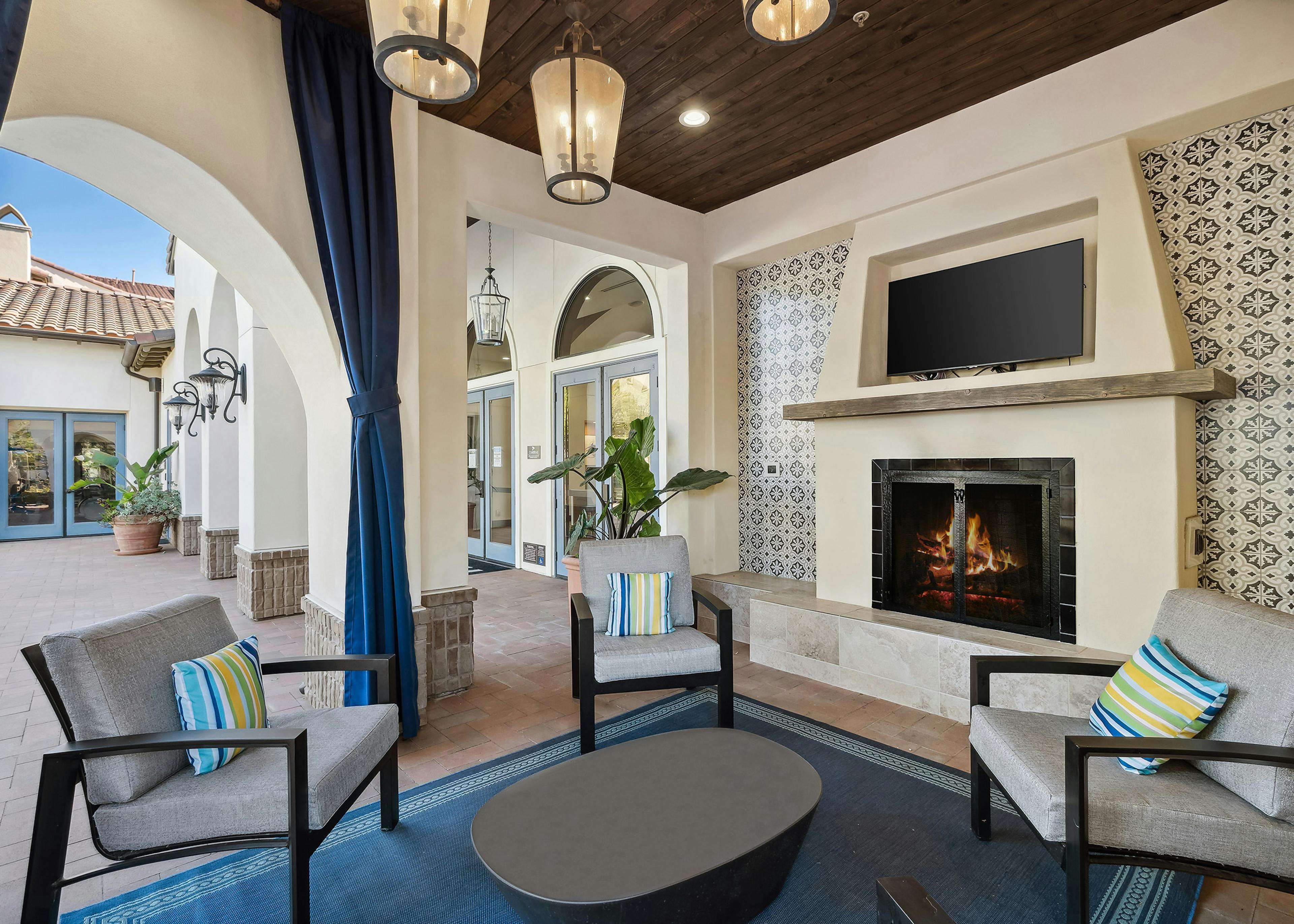 Private nook with big screen TV above the fireplace offering plush lounge seating and hanging lights at AMLI Spanish Hills