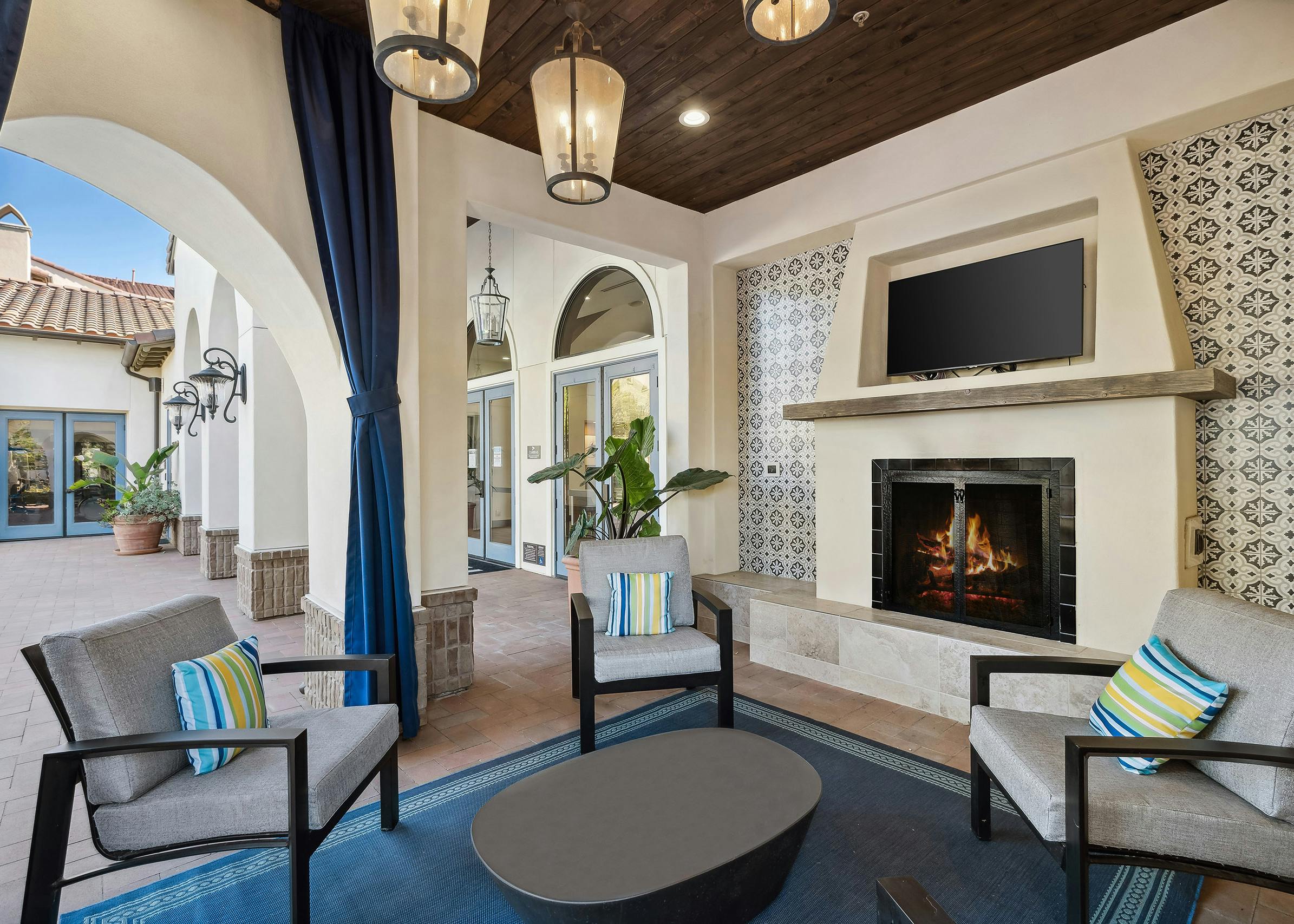 Private nook with big screen TV above the fireplace offering plush lounge seating and hanging lights at AMLI Spanish Hills
