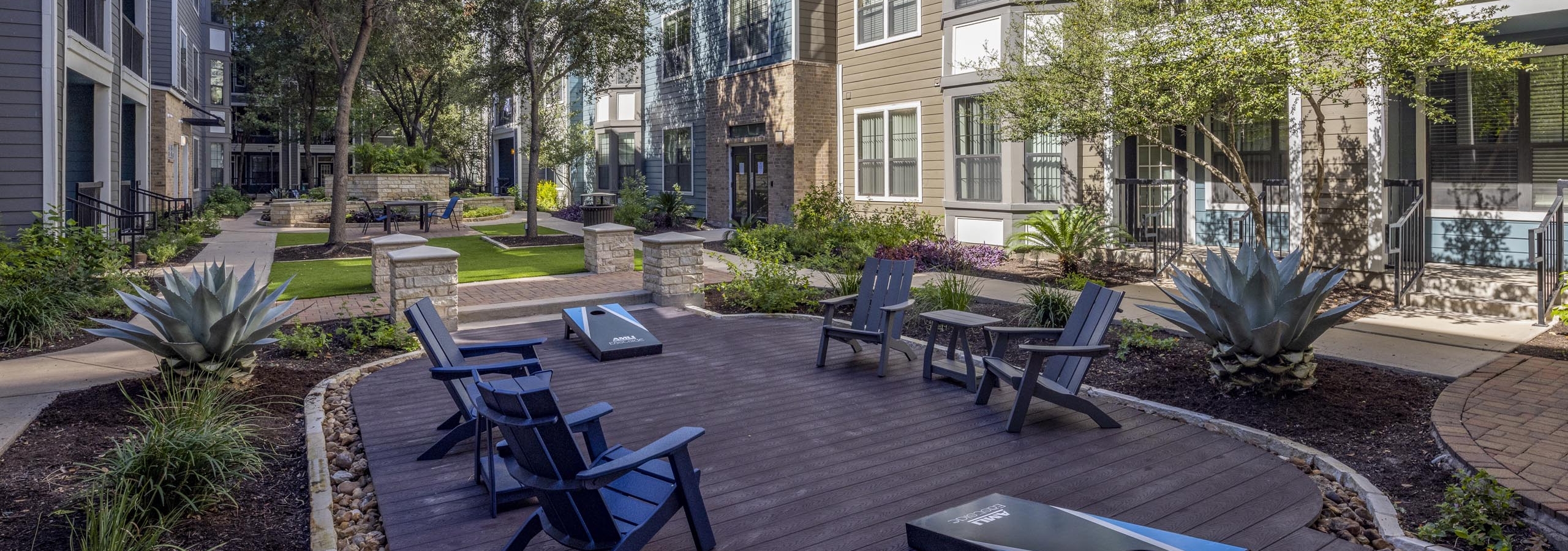 AMLI Eastside apartments courtyard during the day with two beanbag toss stations and dark blue lounge chairs and tables