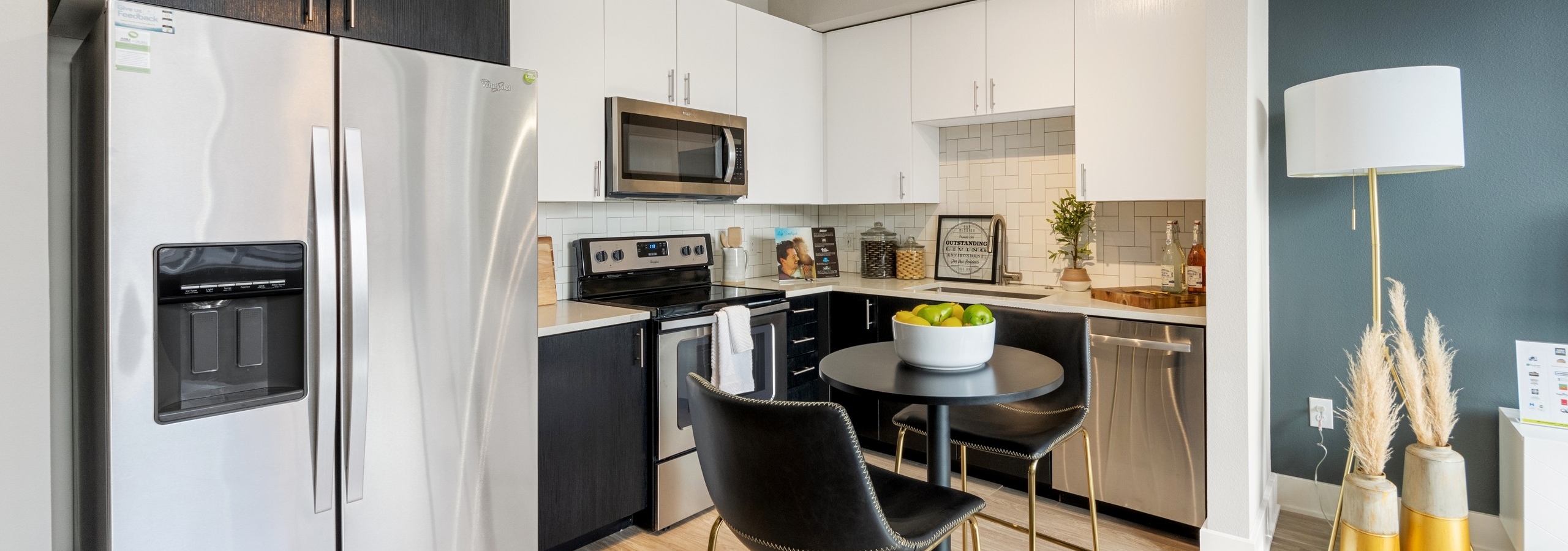 AMLI Riverfront Green apartment kitchen with black and white upper cabinets featuring while tiled backsplash and modern decor