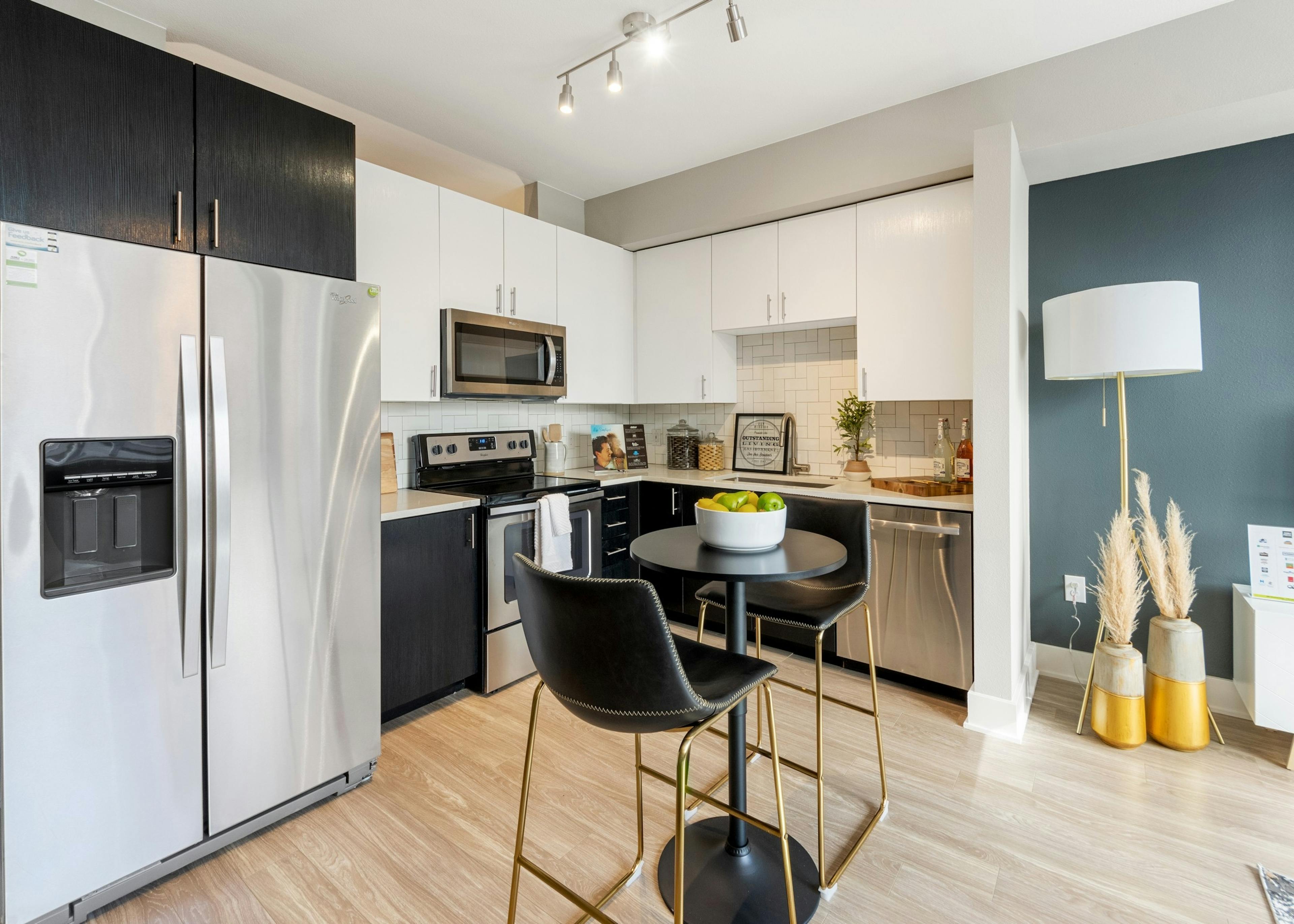 AMLI Riverfront Green apartment kitchen with black and white upper cabinets featuring while tiled backsplash and modern decor