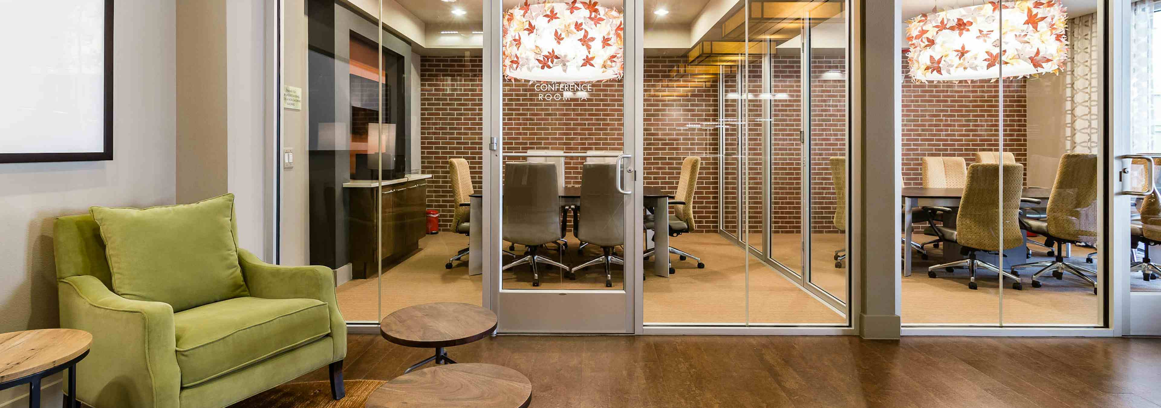 Interior view of AMLI RidgeGate conference rooms equipped with large tables and chairs, ornate chandelier and faux brick wall