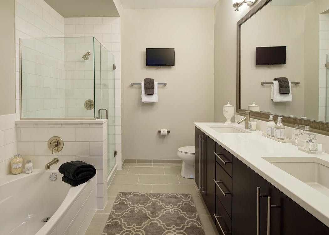 AMLI River North bathroom with a toilet and double vanity along one wall and seperate bathtub and shower along another