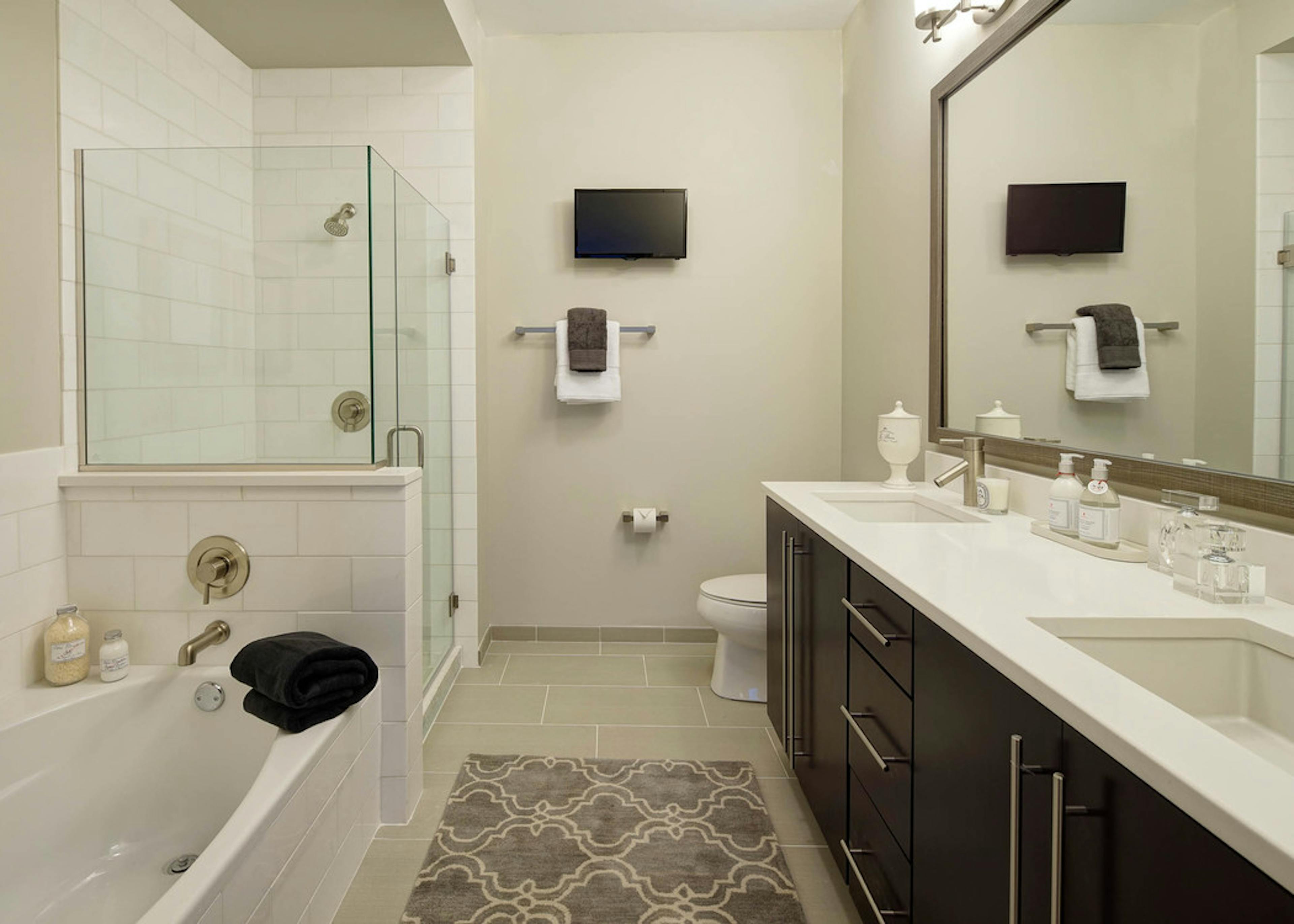 AMLI River North bathroom with a toilet and double vanity along one wall and seperate bathtub and shower along another