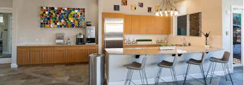Interior view of the resident kitchen at AMLI Inverness apartments with a granite counter top with bar chairs and chandelier