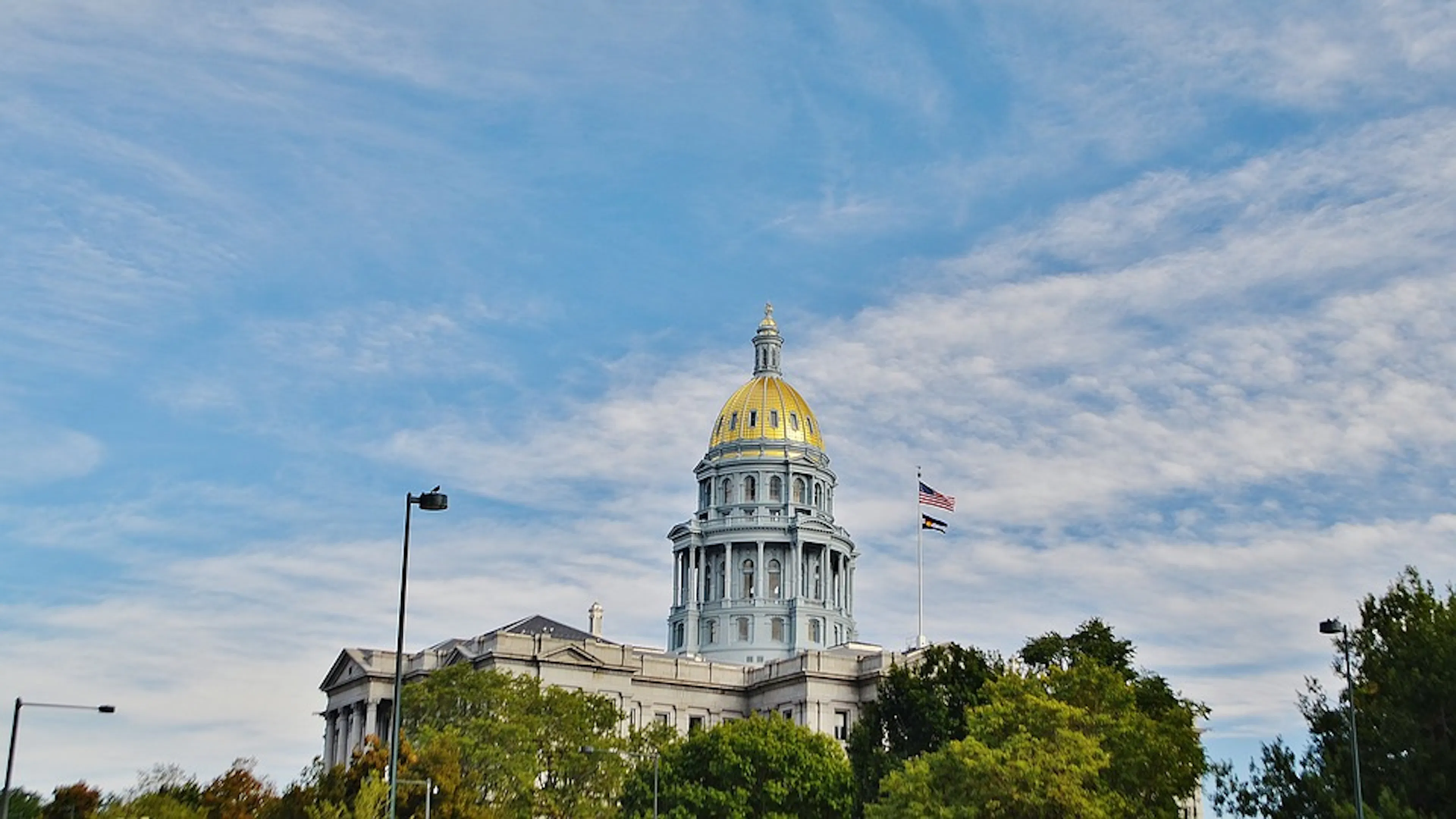 The top of the Denver capitols gold dome against a blue sky  