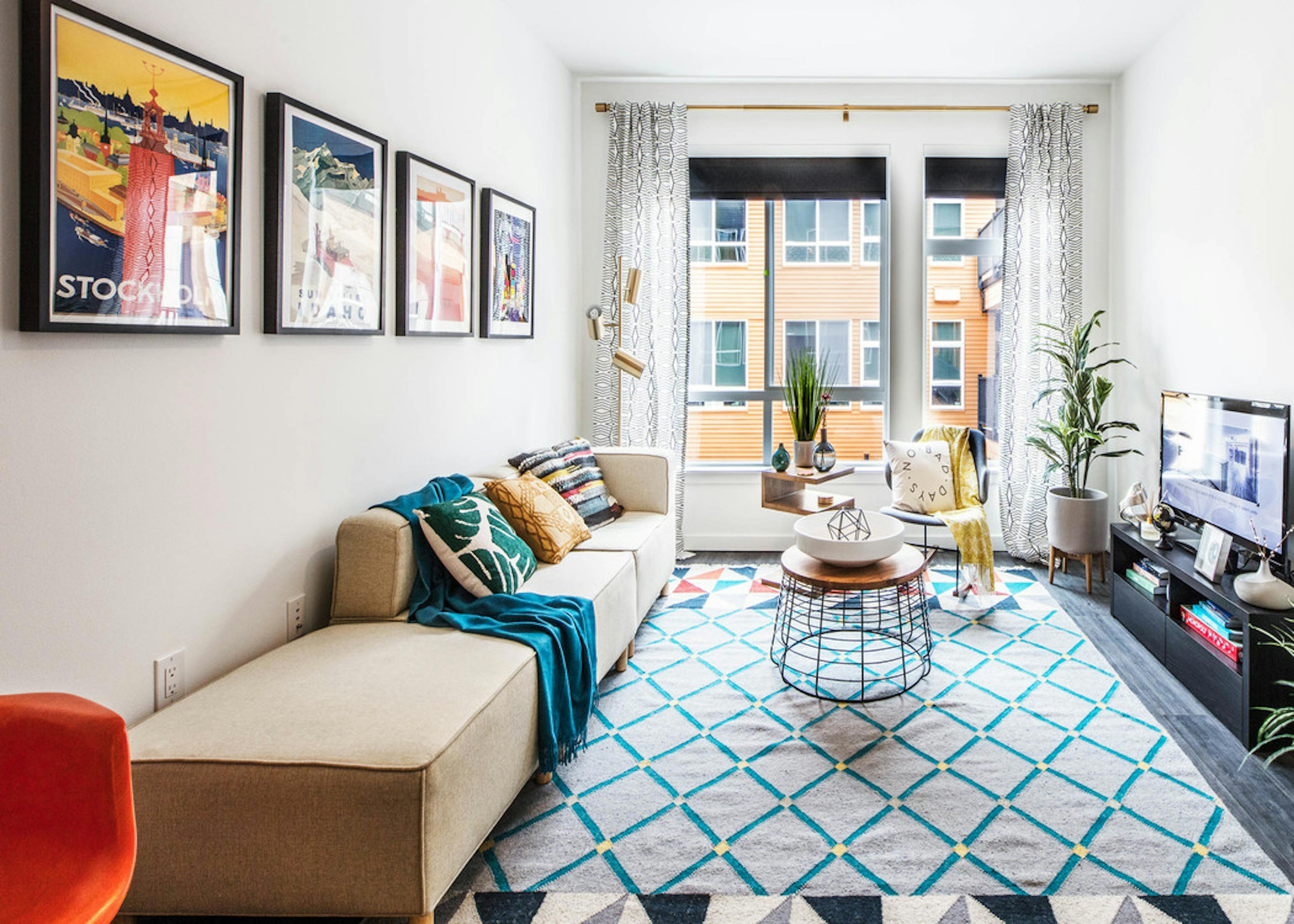 Interior view of a living room at AMLI Wallingford with TV view of kitchen with colorful carpets 