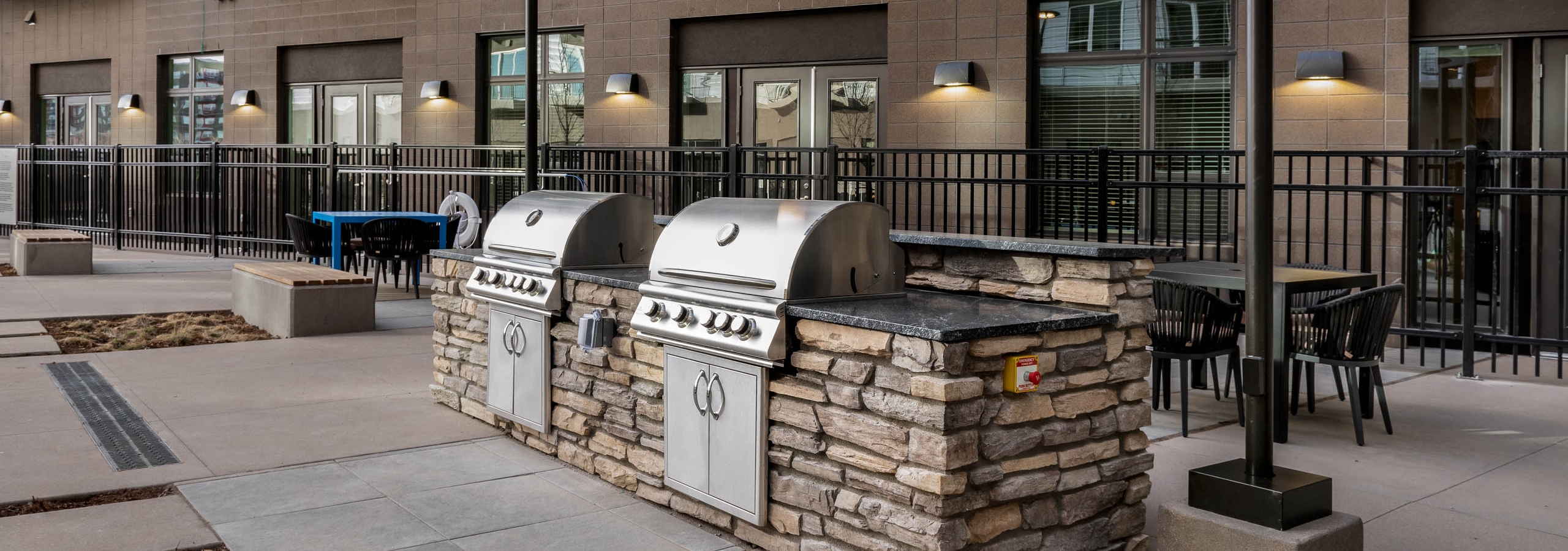 Exterior view of a grilling area at AMLI Art District with multiple tables with chairs and benches and apartment balconies