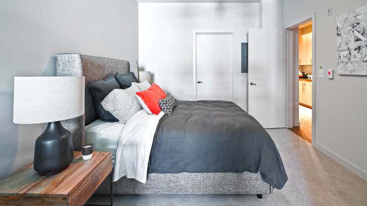 Apartment bedroom at AMLI South Lake Union with a queen-sized bed and bedside table with a lamp and view of the walk in closet