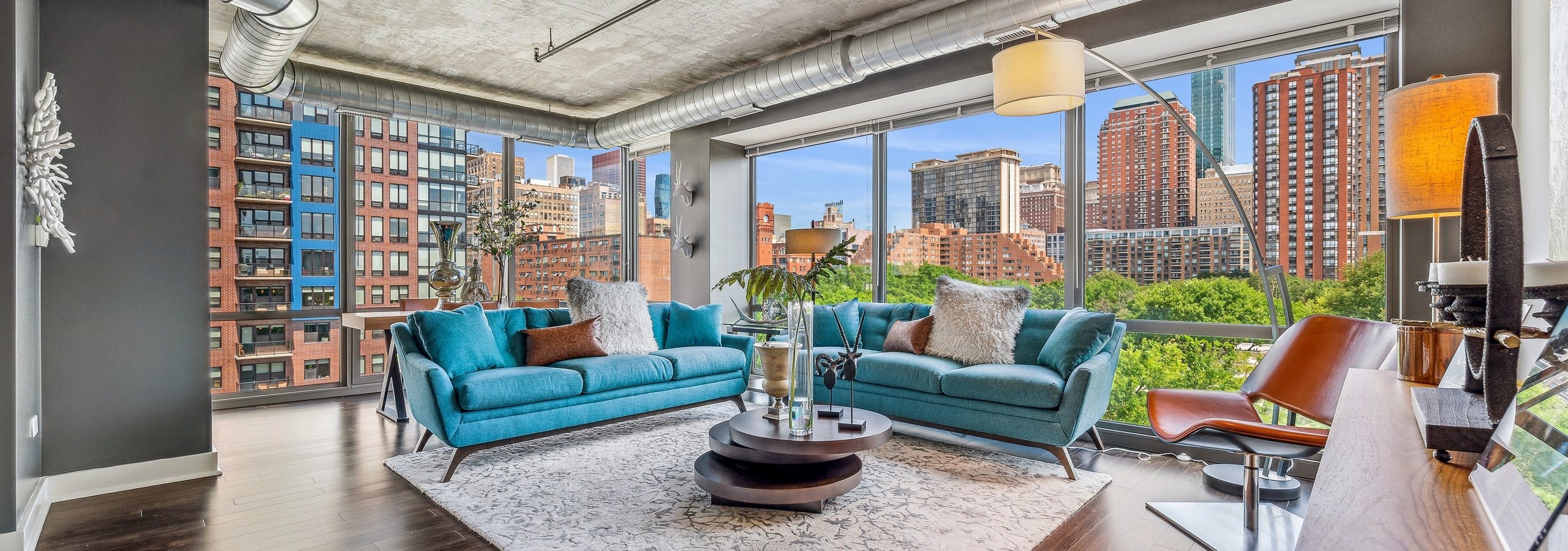 AMLI 900 living room with floor to ceiling view of city and blue couches with dark wood floors and distressed ceilings