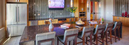 Resident kitchen at AMLI Denargo Market apartments with a long table and chairs and a tile back splash with a fridge and tv