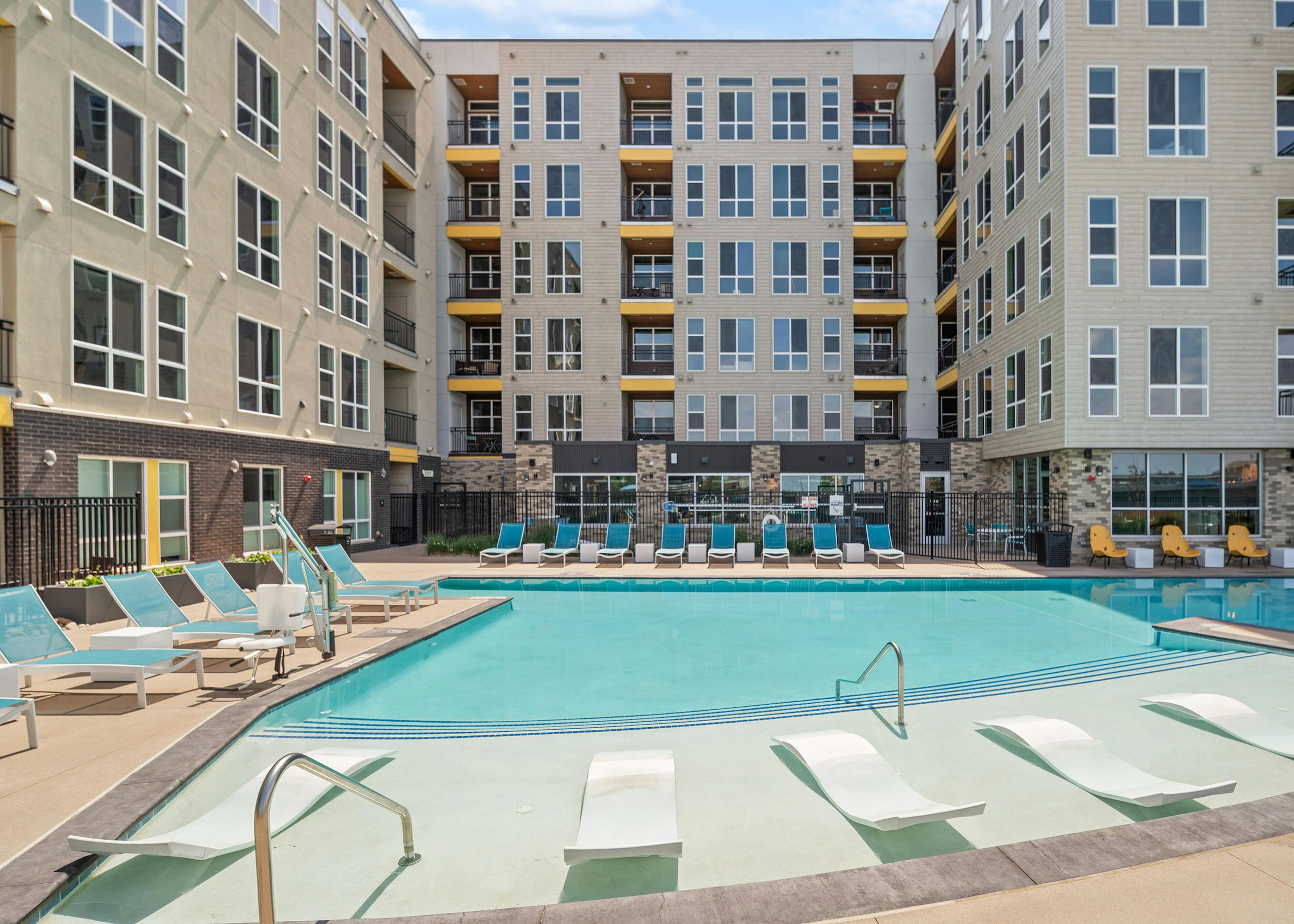 Courtyard pool with lounge seating inside and outside of water surrounded by AMLI RiNo beige and brown building 