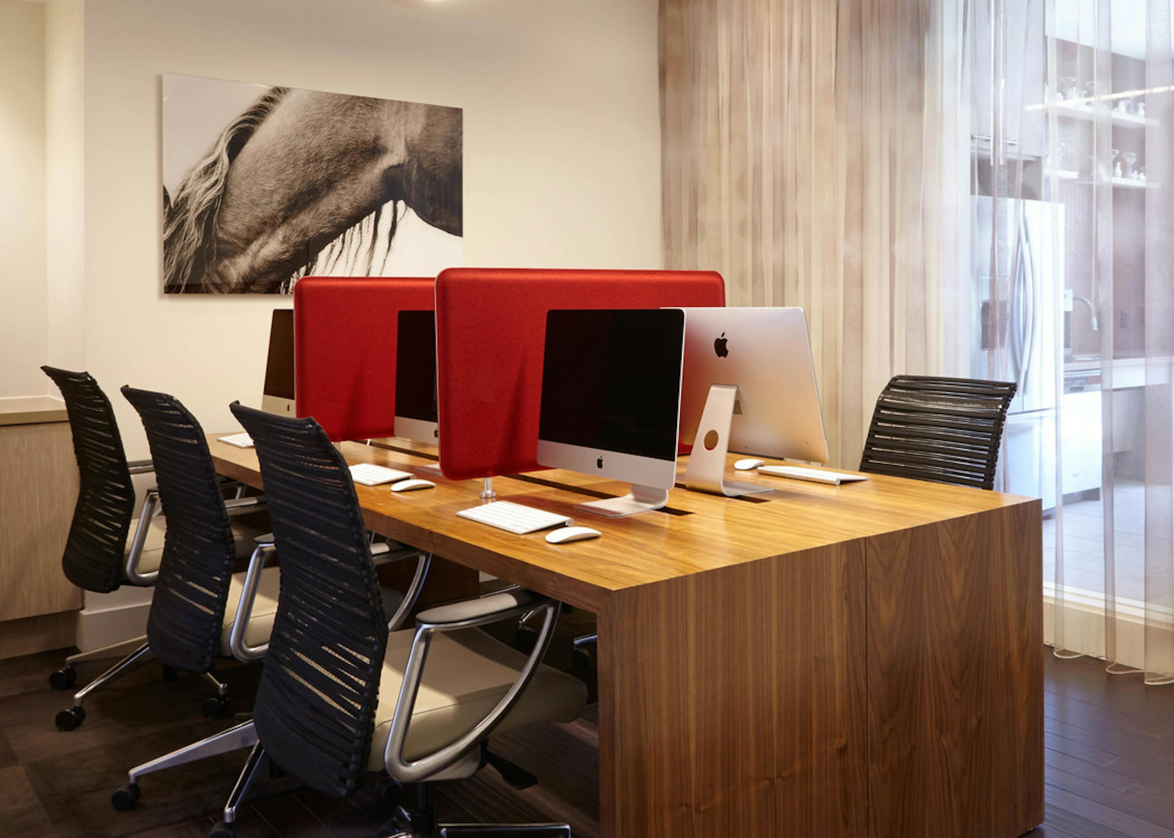 AMLI on Riverside business center with long wooden desk with black office chairs and Apple computers with bold red separators
