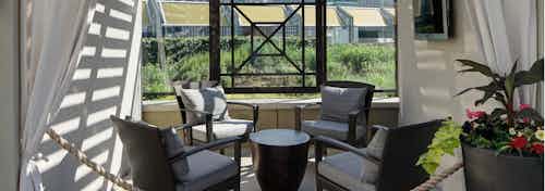 AMLI River North cabana view at dusk with four wicker chairs around a small table surrounded by flowing white curtains