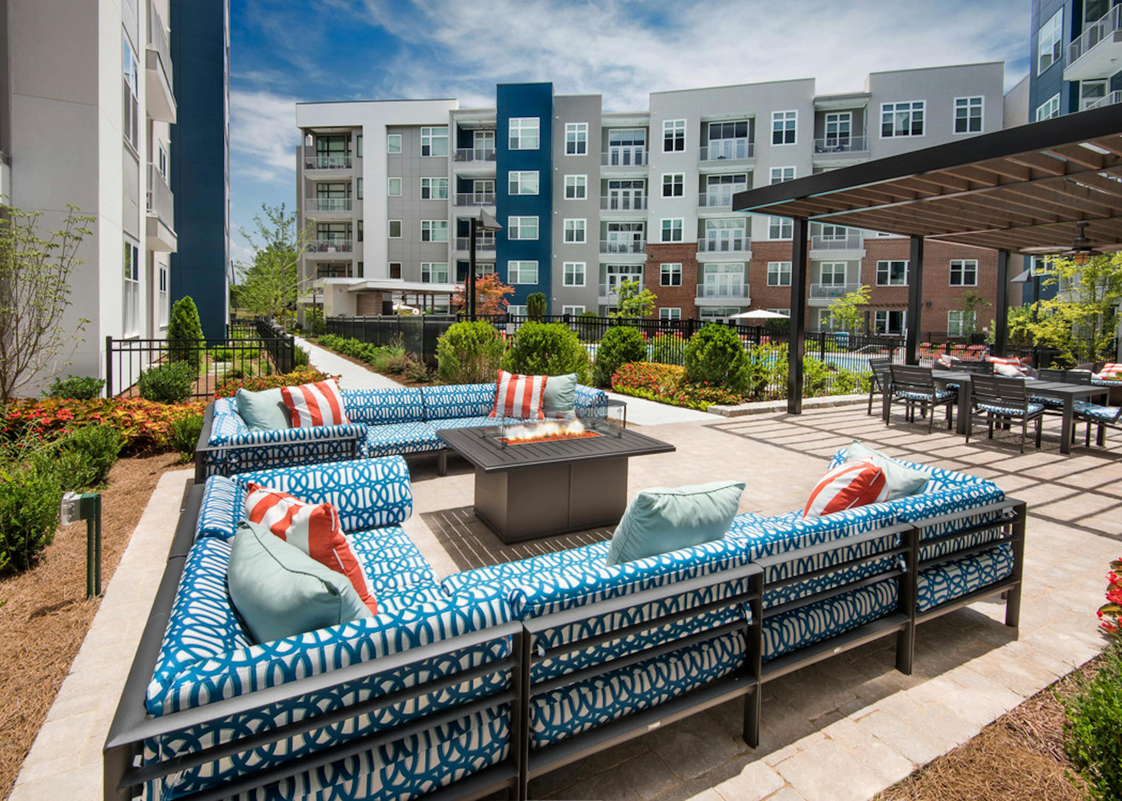 Two patterned blue L couches with a fire pit in the center and green foliage surrounding the patio area at AMLI Buckhead