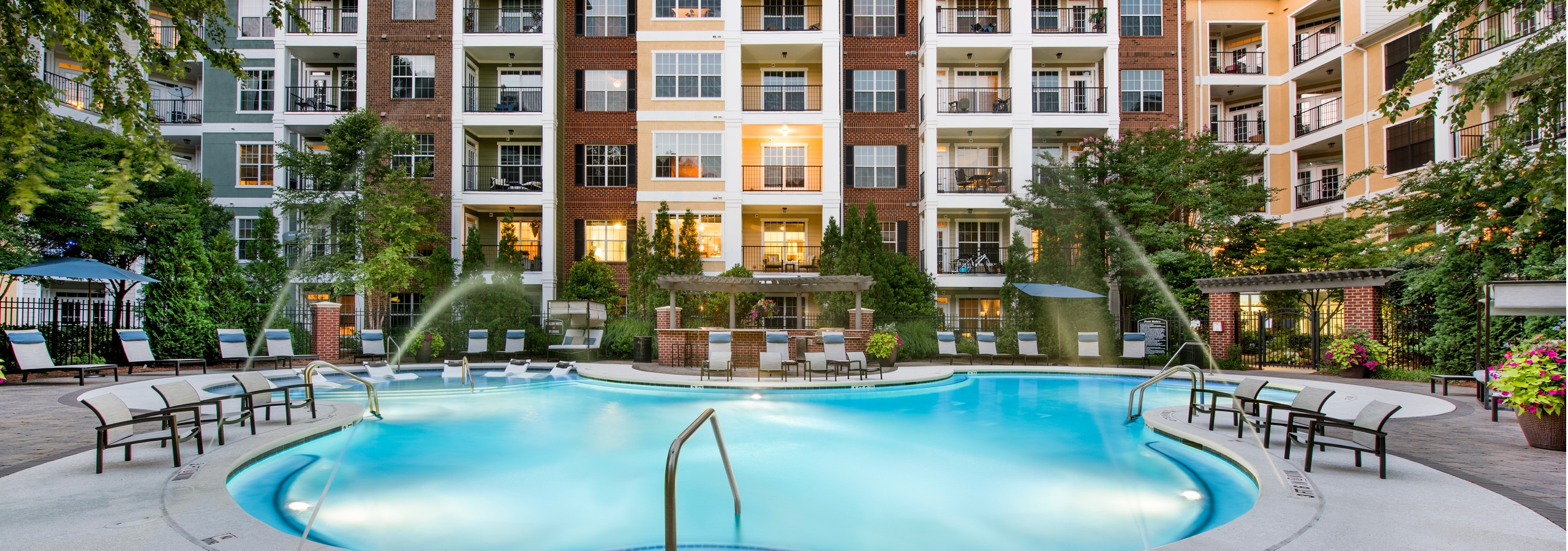 View from AMLI North Point facing the brick facade of the building with tilted vertical sprinklers spraying above the water