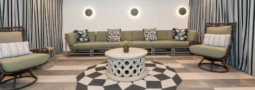 Daytime view of an outdoor courtyard hangout cave with long couch, striped curtains and checkered rug at AMLI Park Broadway