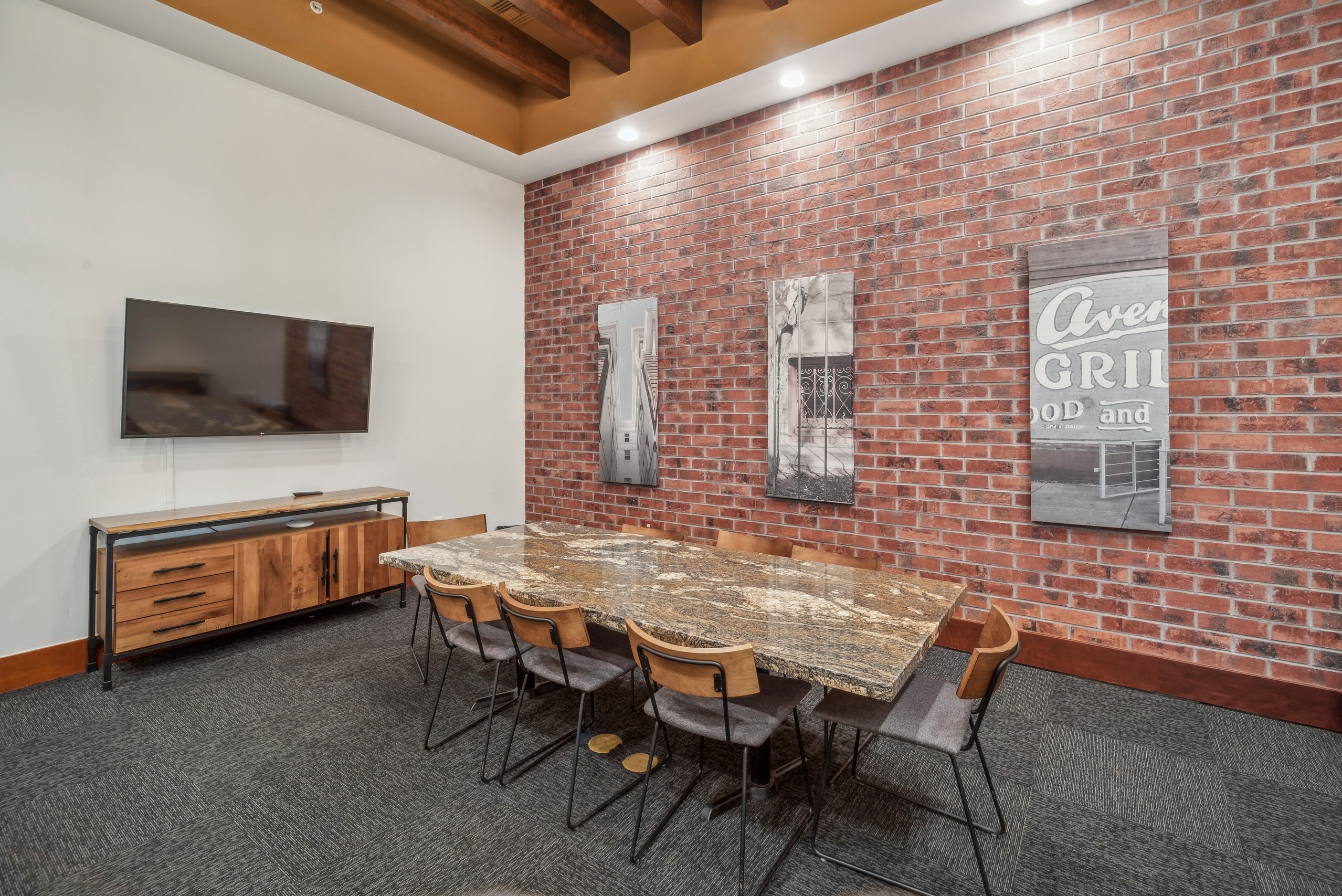 Interior view of a conference room at AMLI Park Avenue apartments with a granite table with 8 chairs and a brick wall