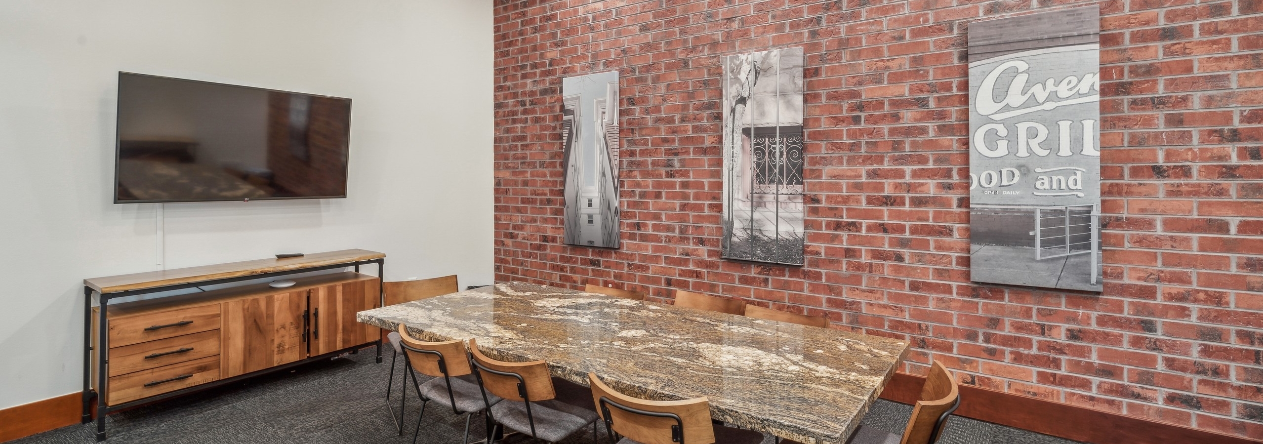 Interior view of a conference room at AMLI Park Avenue apartments with a granite table with 8 chairs and a brick wall