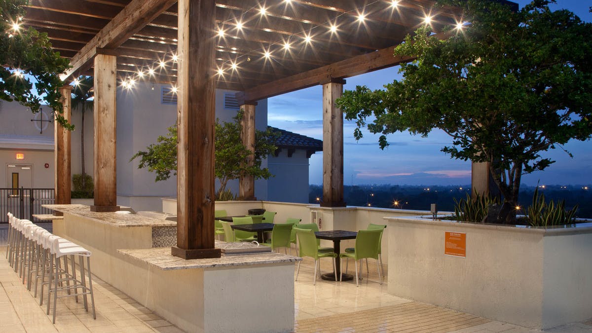 Dusk exterior view of AMLI Dadeland rooftop grill station with hanging lights above