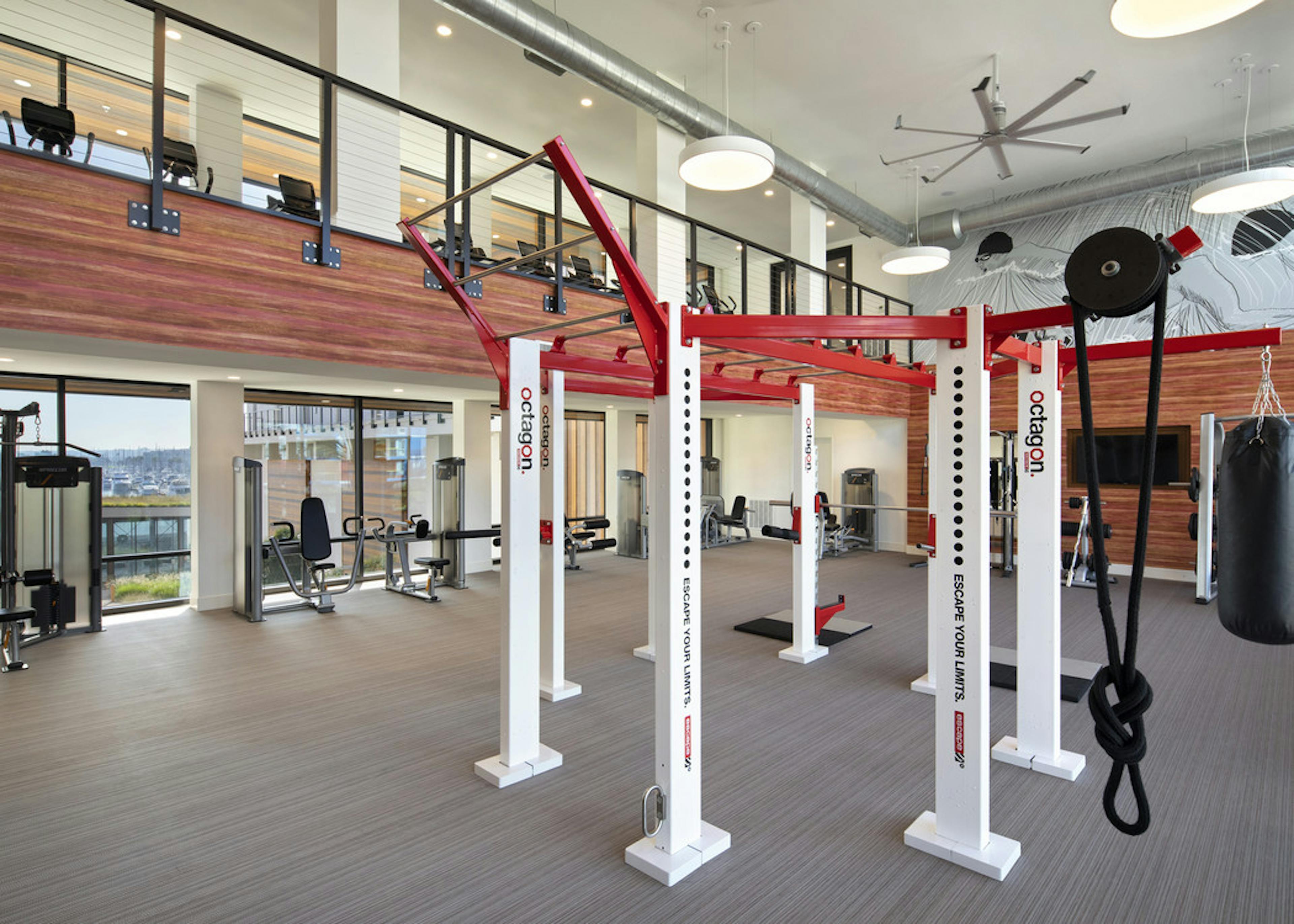 Interior of AMLI Marina Del Rey apartment fitness center with strength workout equipment and motion cage facing the marina