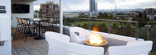 An exterior view of AMLI Riverfront Green roof top deck with fire pit and furniture and mountain view and sky scraper views