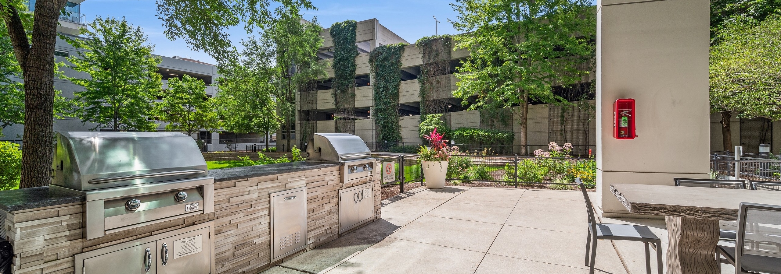 Two large outdoor grills with black countertop on stacked stone base and outdoor seating at AMLI 900 apartment building