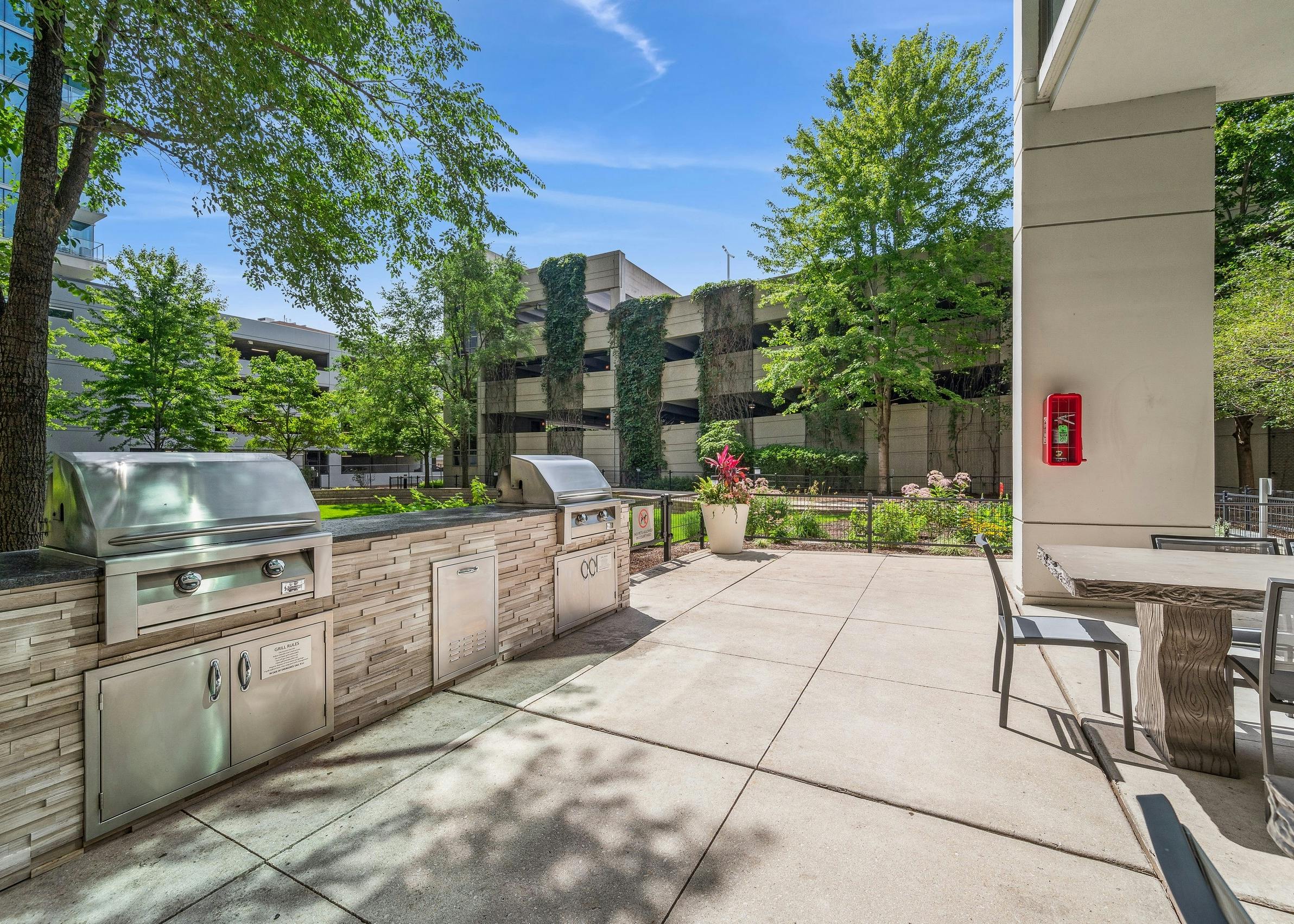 Two large outdoor grills with black countertop on stacked stone base and outdoor seating at AMLI 900 apartment building