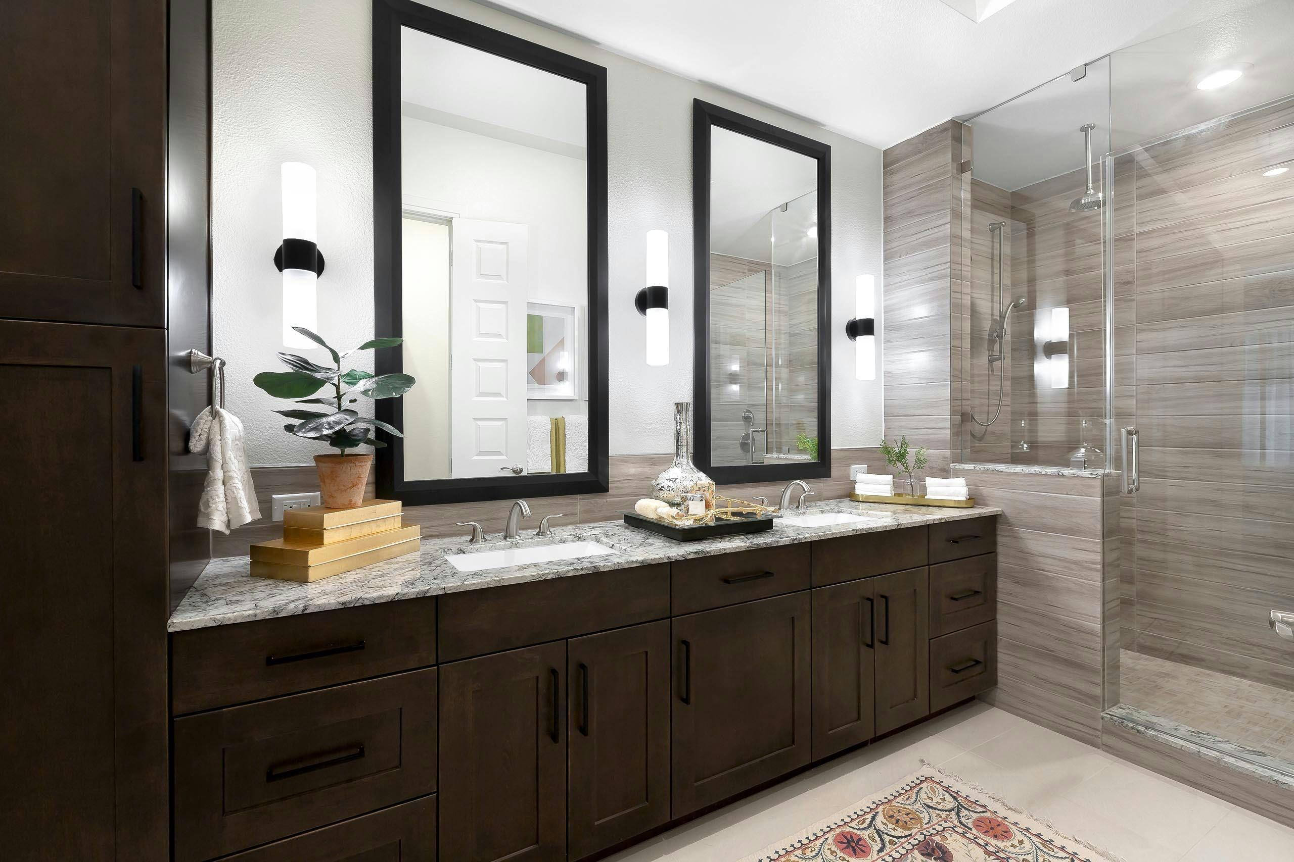 AMLI Lakeline apartment bathroom with dark wood double vanity with granite counter and 2 mirrors above and a walk in shower
