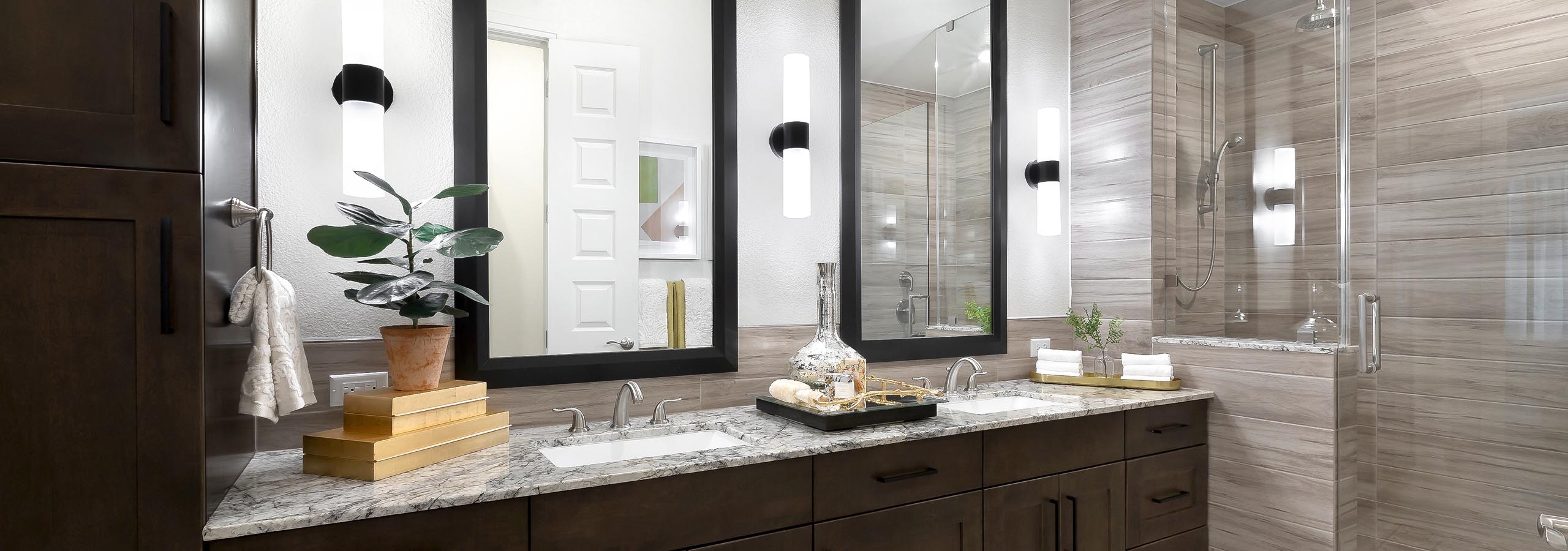 AMLI Lakeline apartment bathroom with dark wood double vanity with granite counter and 2 mirrors above and a walk in shower