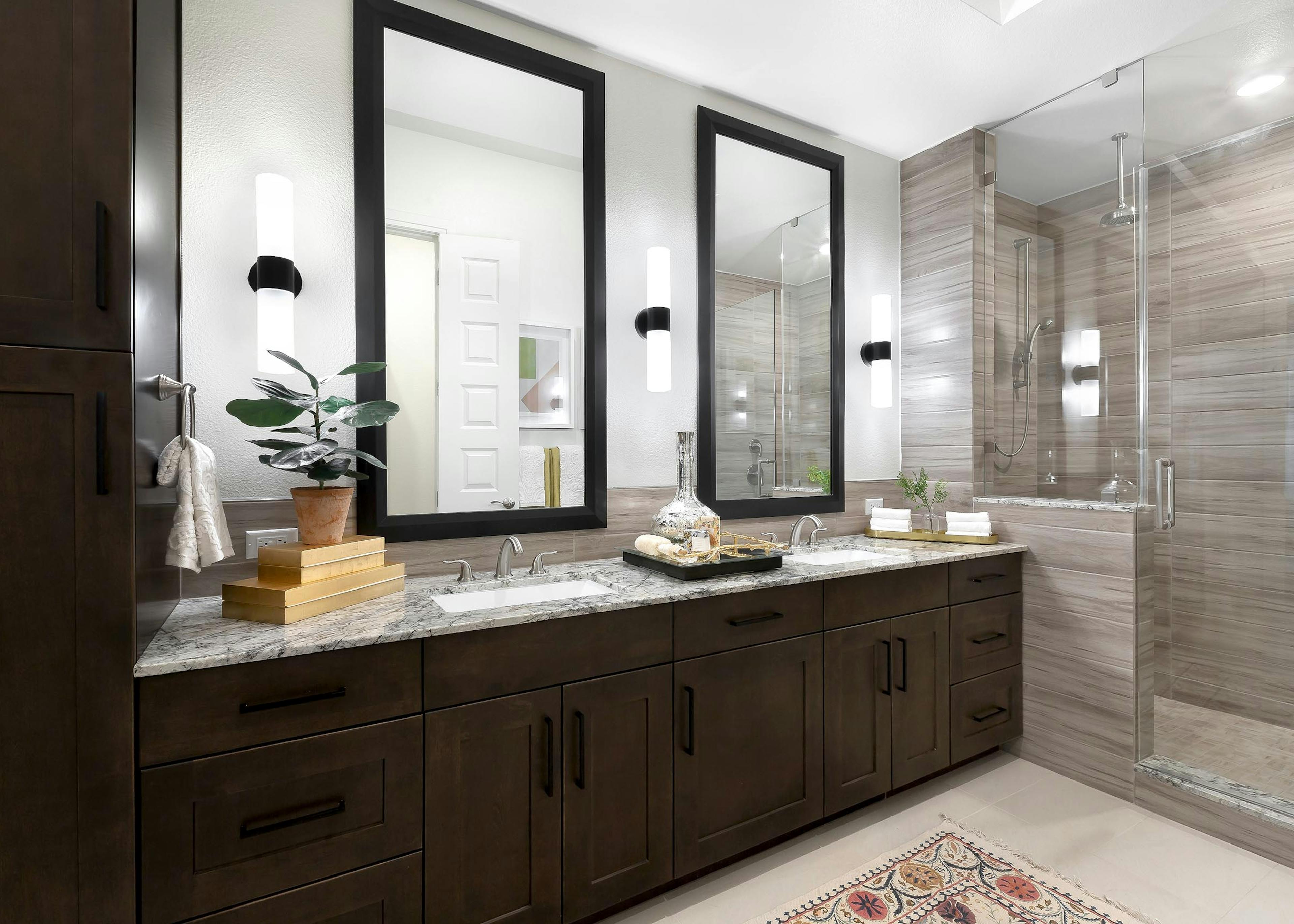 AMLI Lakeline apartment bathroom with dark wood double vanity with granite counter and 2 mirrors above and a walk in shower