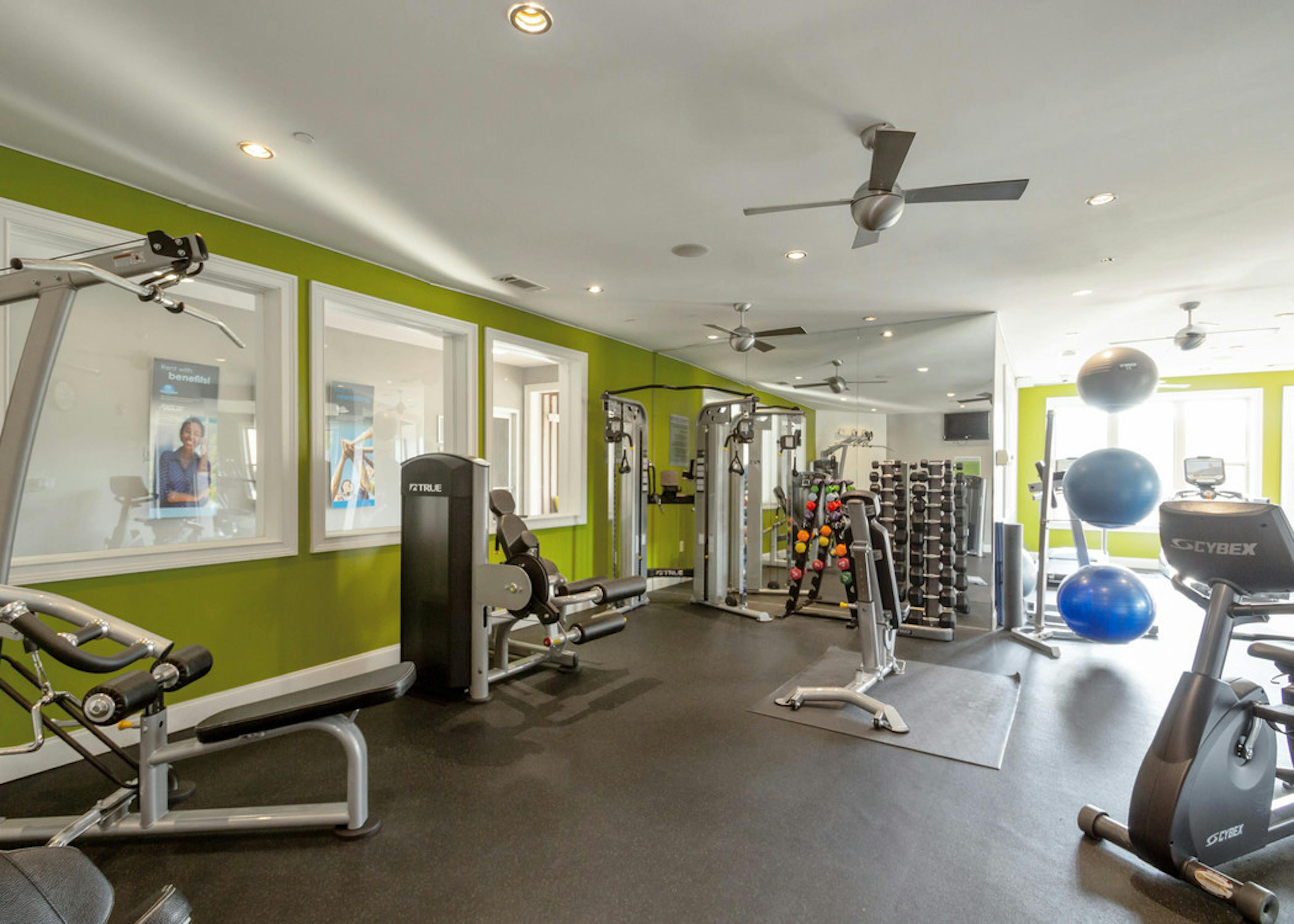 Interior of AMLI Lindbergh gym amenity with green walls and fully equipped fitness equipment with three blue exercise balls