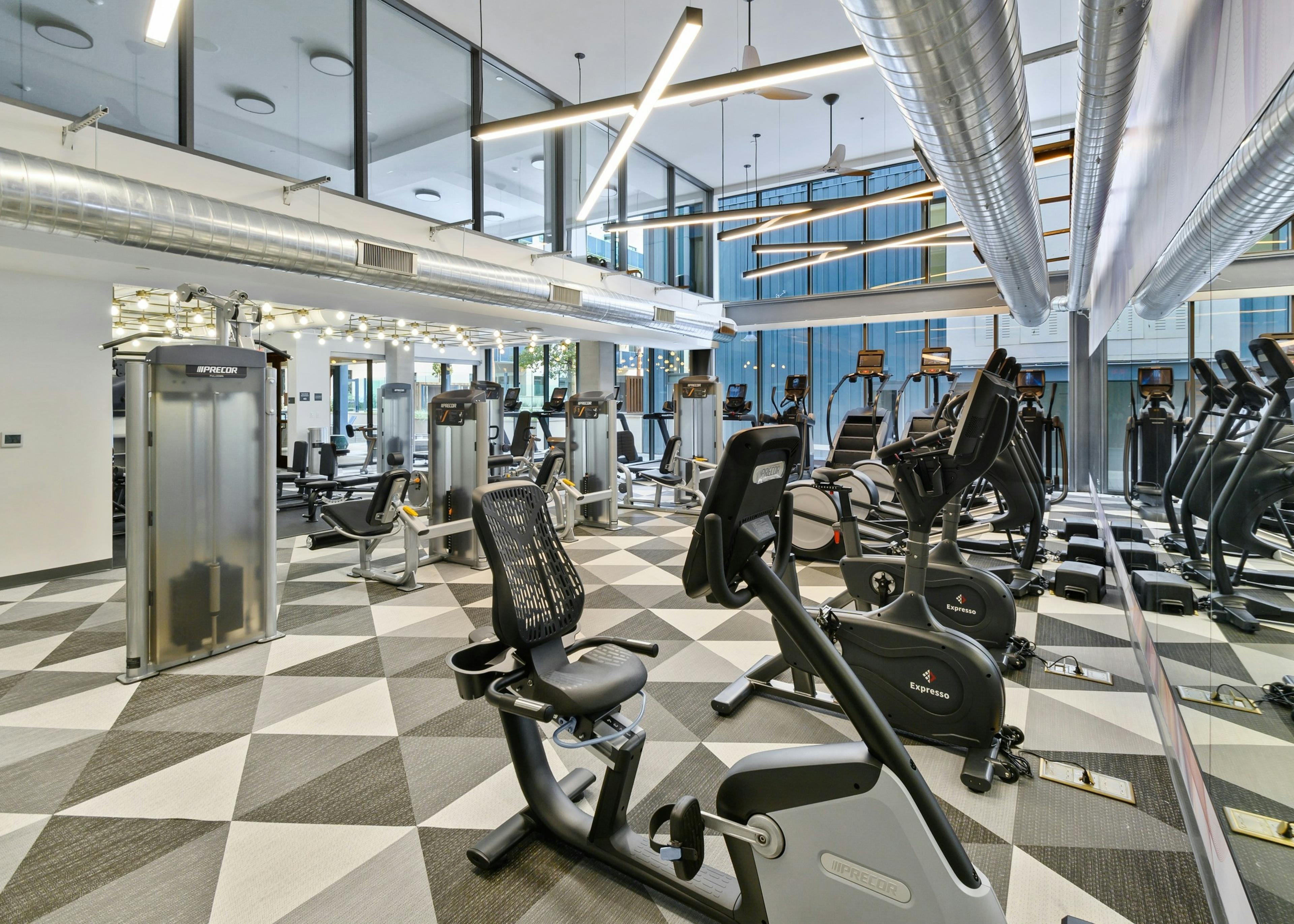 Interior view of fitness center with numerous cardio machines on custom checkered flooring at AMLI Old Pasadena apartments
