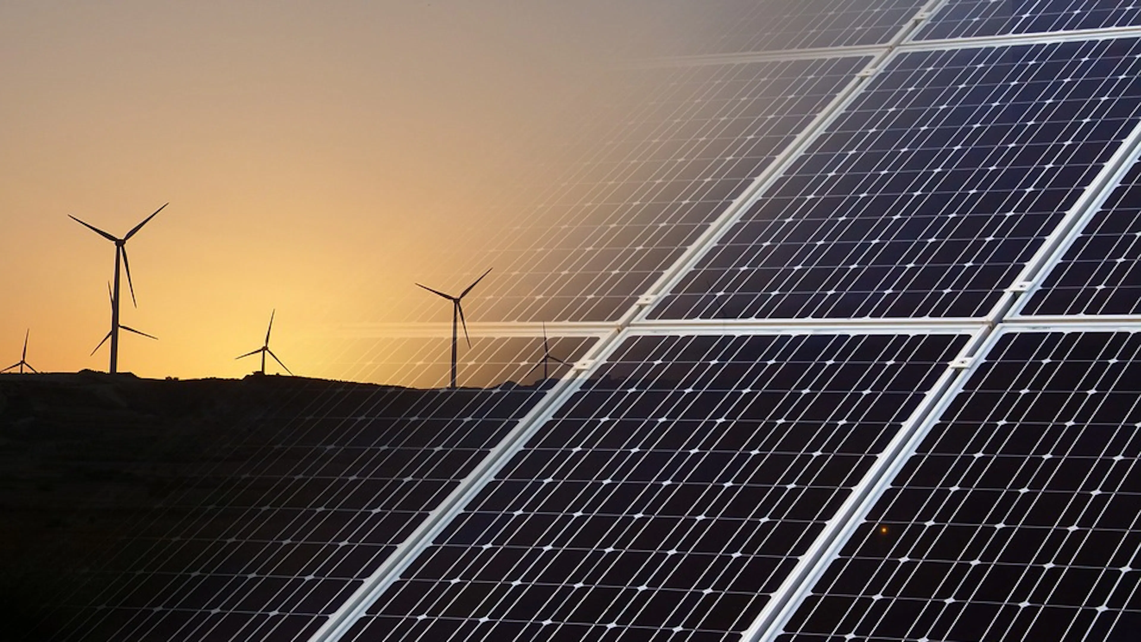 A superimposed image of a set of solar panels over an image of wind turbines set against a sunset sky