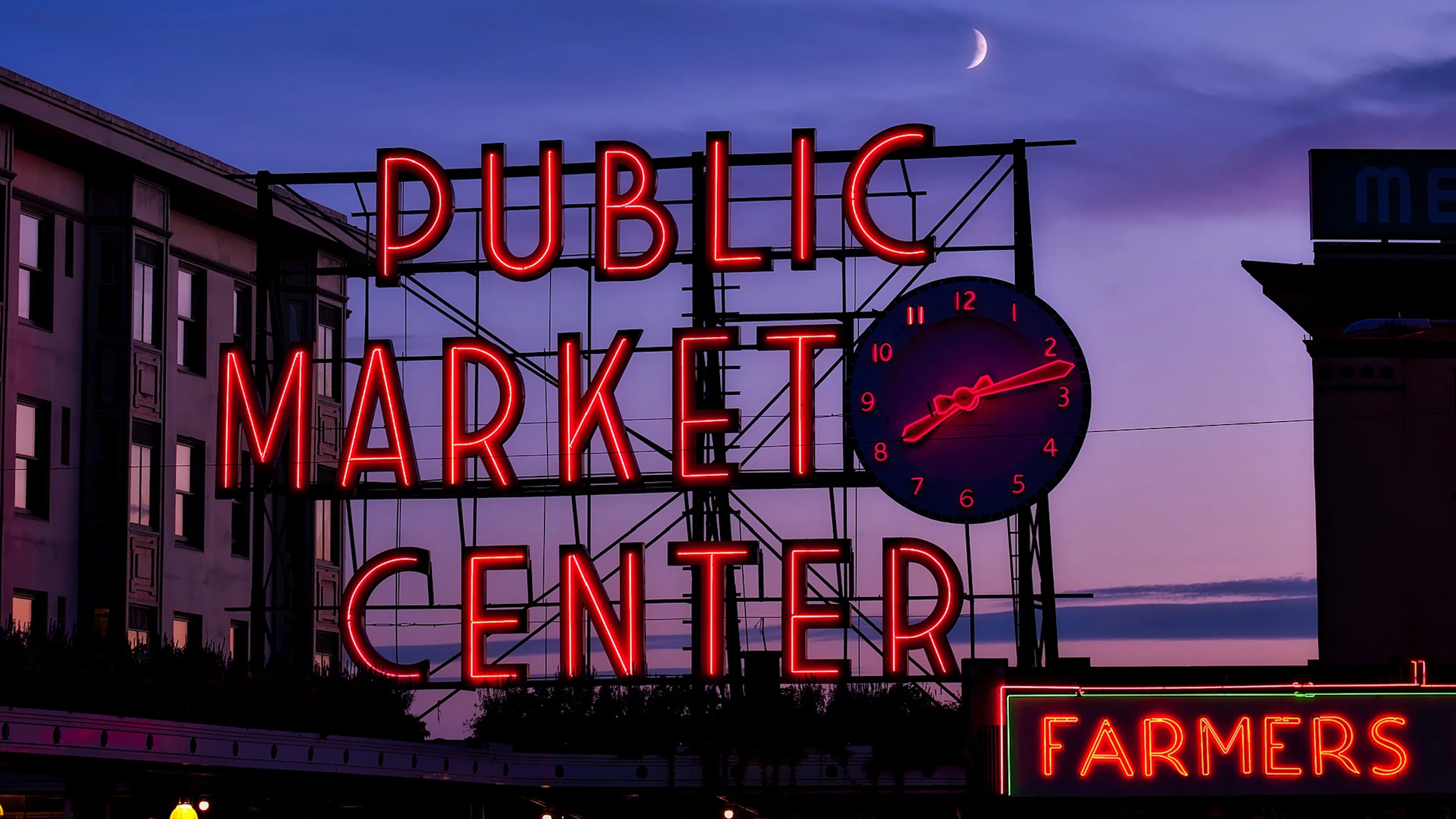 The Public Market Center sign at Pike Place Market lit in neon red against a moonlit sky