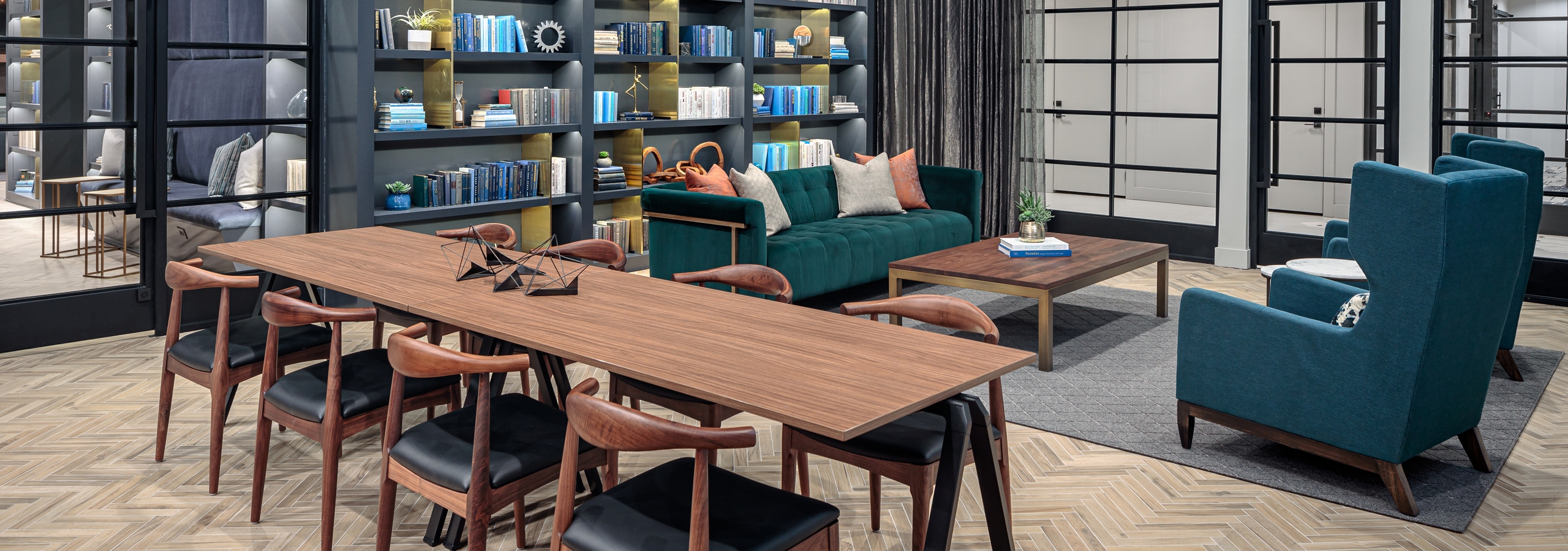 Interior of AMLI Addison tap room with a long wooden table with eight chairs and teal couch seating area in the background