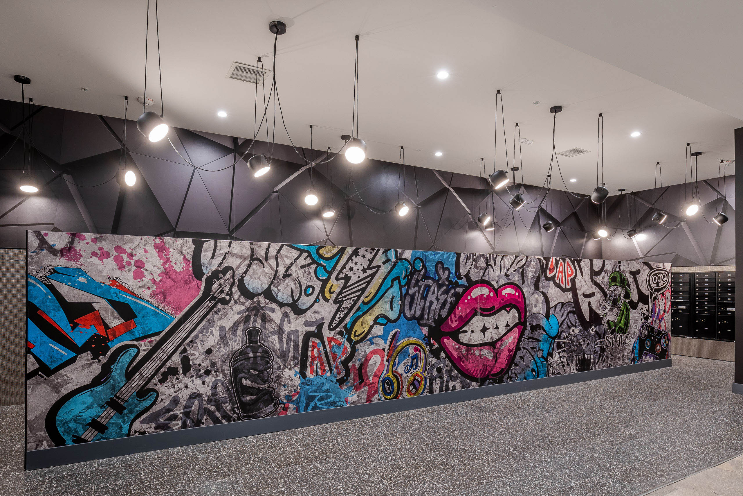Mail room wall mural at AMLI Midtown Miami apartments with colorful graffiti wall art and numerous hanging spotlights 