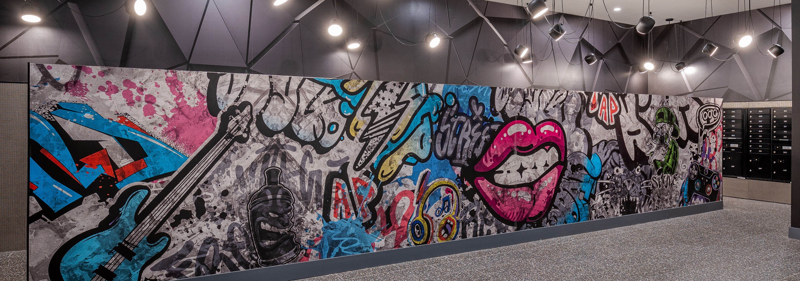 Mail room wall mural at AMLI Midtown Miami apartments with colorful graffiti wall art and numerous hanging spotlights