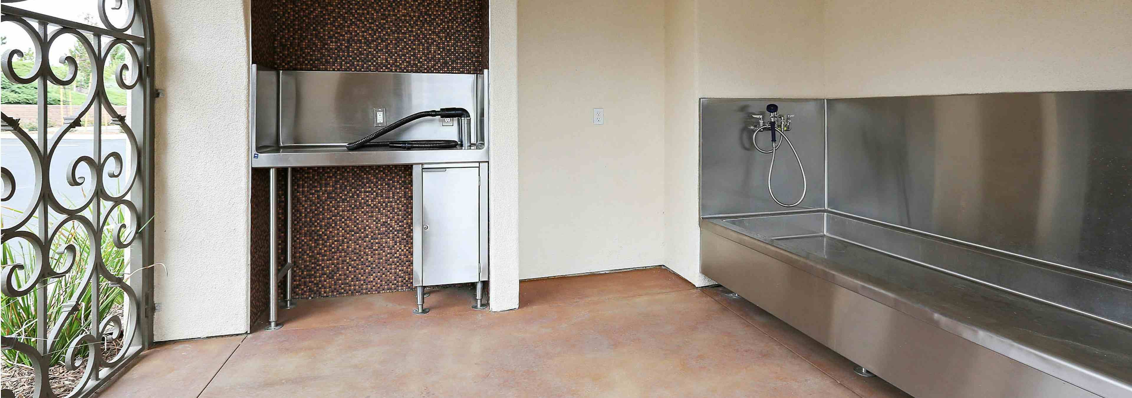 Interior daytime view of paw wash at AMLI Spanish Hills apartment building with stainless tub, grooming counter and dryer